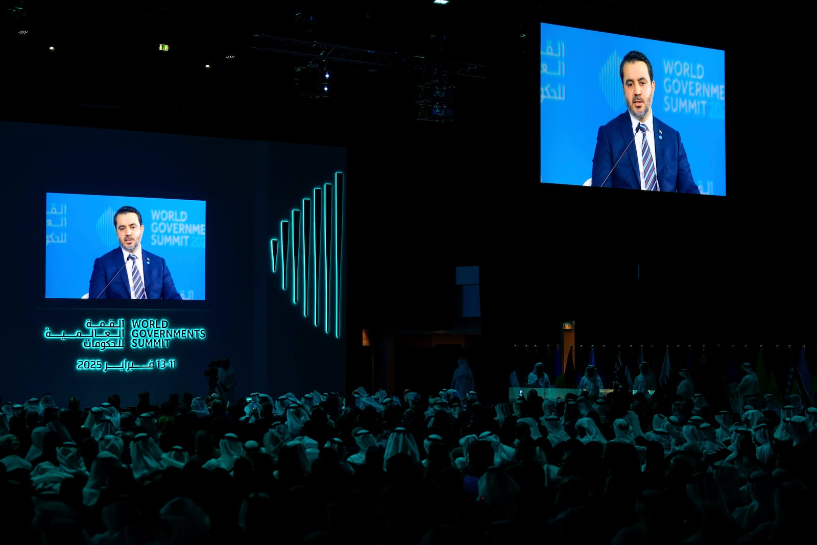 Delegates listen to Syria's Interim Foreign Minister Asaad Al-Shibani shown on giant screens as he talks to Kuwaiti journalist Ammar Taqi during the World Governments Summit in Dubai, United Arab Emirates, Wednesday, Feb. 12, 2025. (AP Photo/Altaf Qadri)