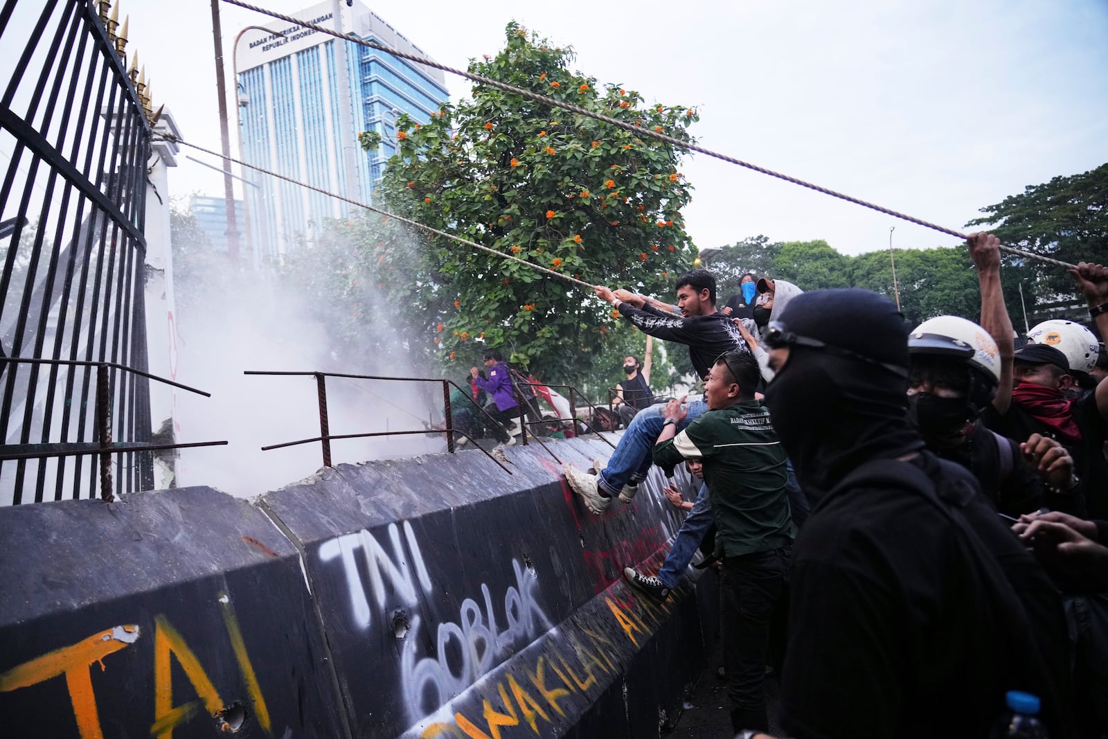 Protesters tear down a part of the fence of the parliament building during a rally in Jakarta, Indonesia, Thursday, March 20, 2025, against the passing of a controversial revision of a military law that will allow military officers to serve in more government posts without resigning from the armed forces. (AP Photo/Tatan Syuflana)