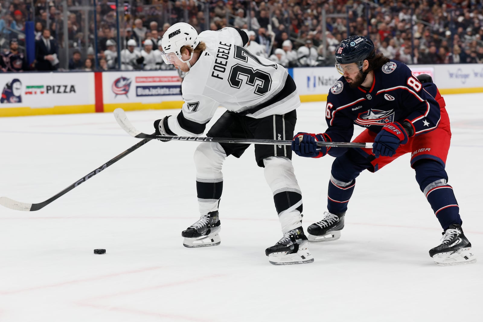 Columbus Blue Jackets' Kirill Marchenko, right, tries to steal the puck from Los Angeles Kings' Warren Foegele, left, during the first period of an NHL hockey game Saturday, Jan. 25, 2025, in Columbus, Ohio. (AP Photo/Jay LaPrete)