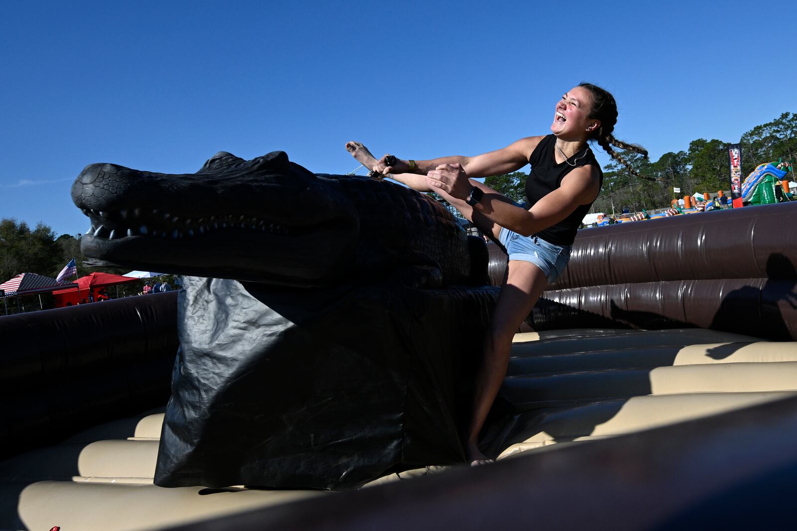 Cheyenne Chaves, of DeLand, Fla., falls off of a mechanical alligator during the Florida Man Games, Saturday, March 1, 2025, in Elkton, Fla. (AP Photo/Phelan M. Ebenhack)