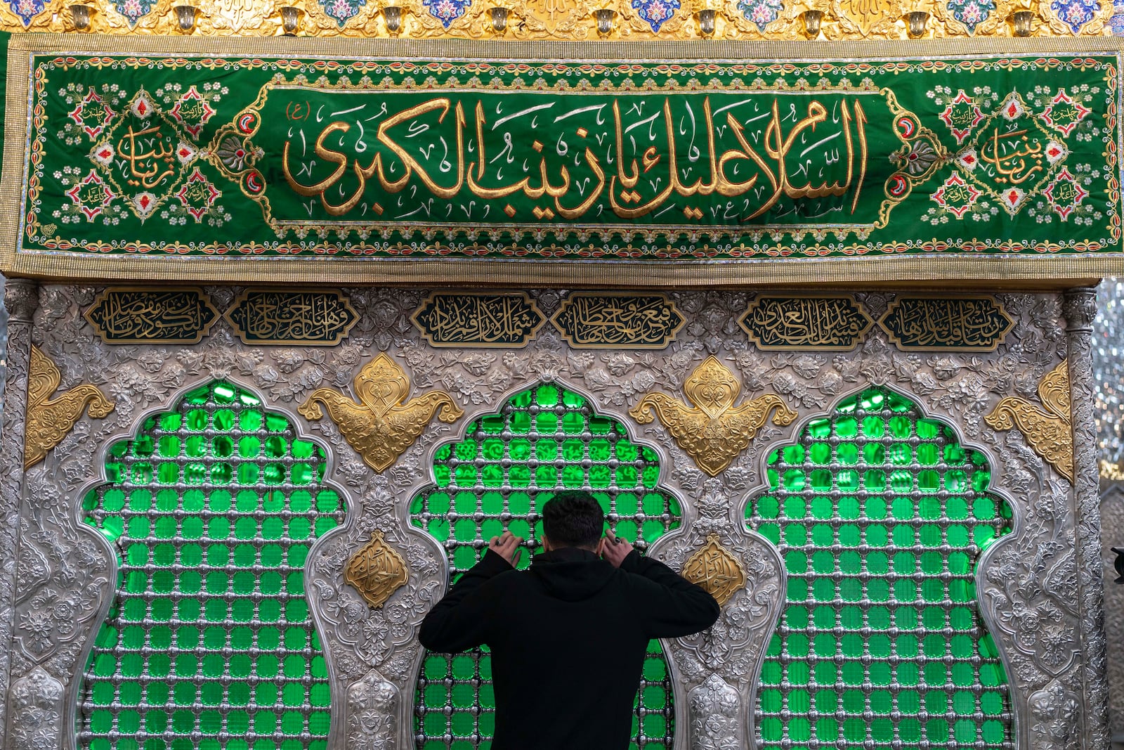 A man carries his child as they pray at the shrine of Sayyida Zaynab, the granddaughter of Prophet Mohammad, in Damascus, Syria, Saturday, Jan. 11, 2025. (AP Photo/Mosa'ab Elshamy)