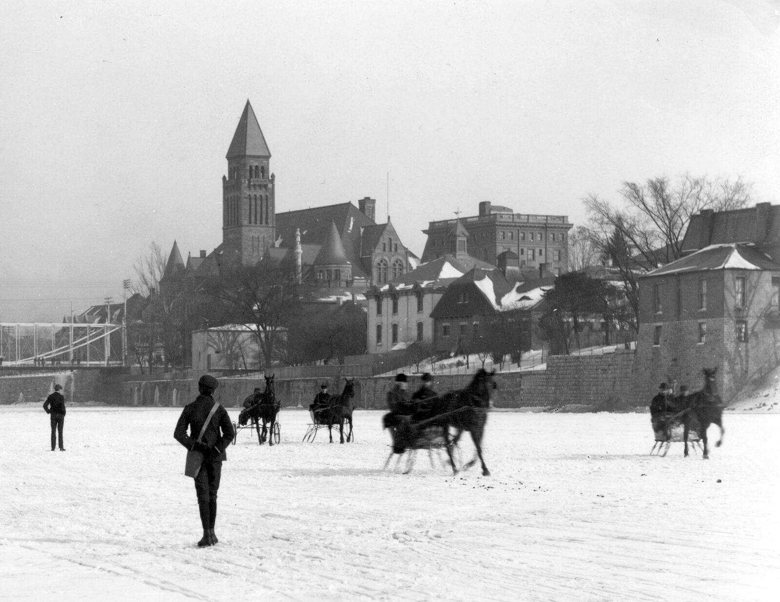 Daytonians ice skating on the Great Miami River.  The picture was taken from the river, looking east toward the Main Street Bridge, which can be seen in the background.  The old steel bridge in the picture was replaced in 1902 with a steel concrete-bridge.  DAYTON METRO LIBRARY