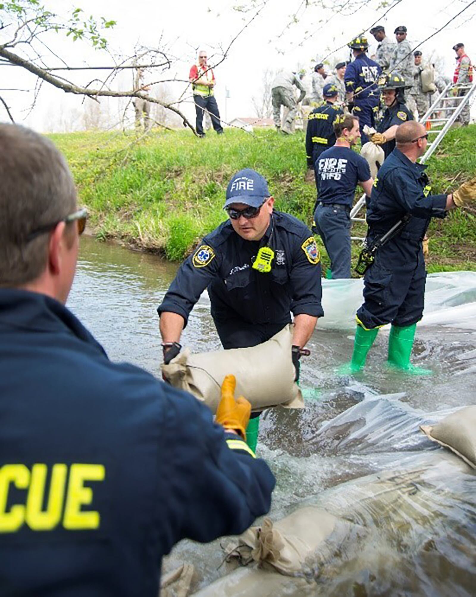 Tim Howells, 788th Civil Engineering Squadron Fire Department, passes a sandbag on as part of an assembly line helping to build a dam in Hebble Creek May 2, 2018, on Wright-Patterson Air Force Base. The Wright-Patterson AFB Fire Department was taking part in training on how to handle a fuel spill. U.S. AIR FORCE PHOTO/R.J. ORIEZ