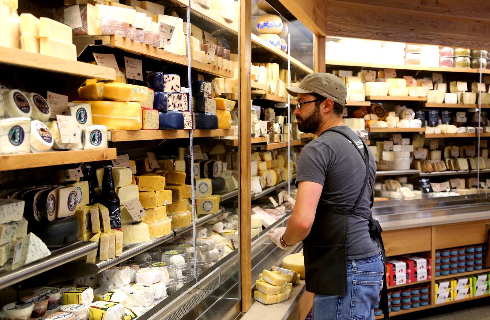 Michael Coffey, a specialty team leader for Whole Foods in Philadelphia, prepares the cheese department in the Centerville Whole Foods store for opening day.  LISA POWELL / STAFF