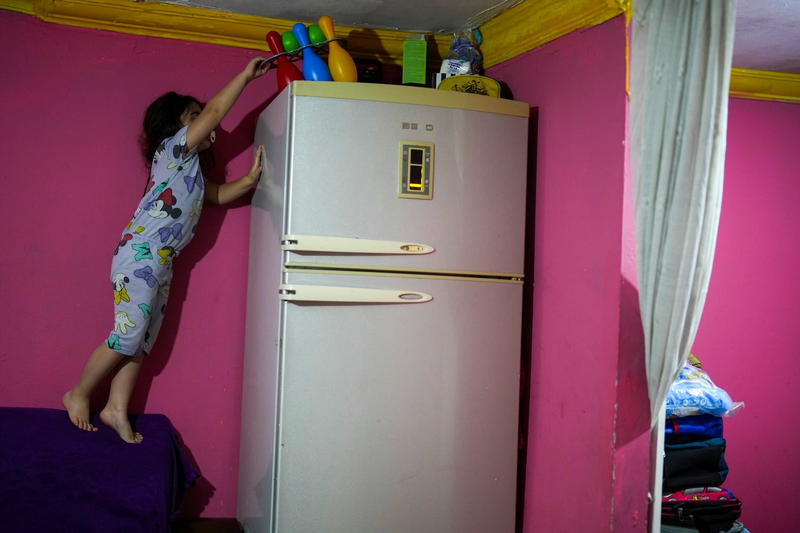 Dilan Sahin, 5, tires to reach her toys in her family's one-room apartment in the Tarlabasi neighborhood in Istanbul, Turkey, Wednesday, Dec. 4, 2024. (AP Photo/Francisco Seco)