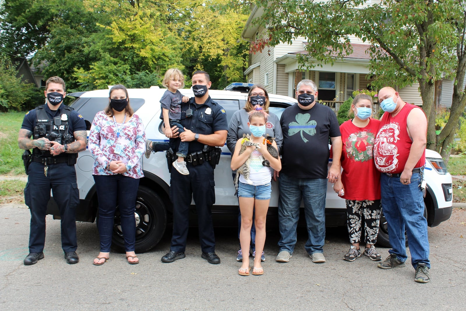 Members of the Dayton police and fire departments stand with a family they helped.