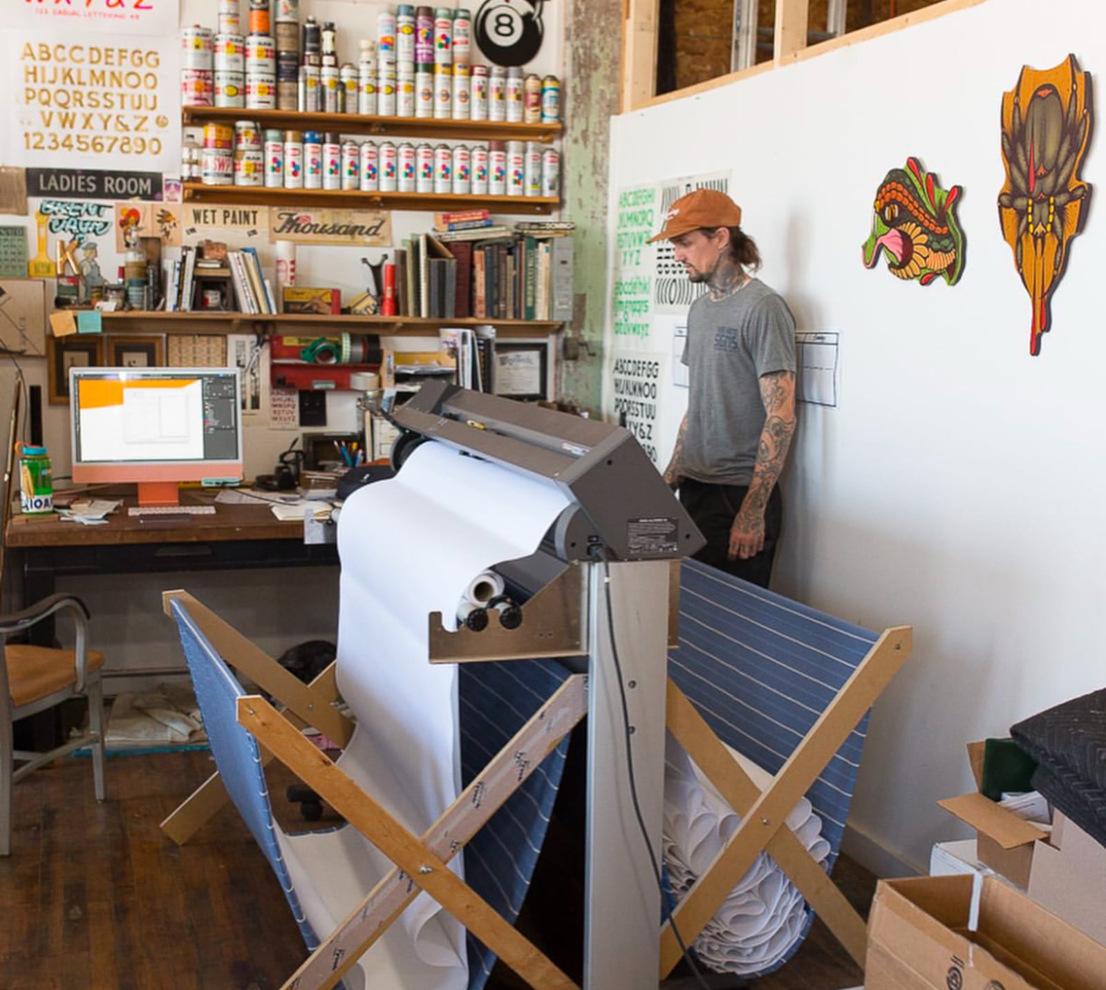 Josh Flohre stands by a plotter machine in the Ink & Hammer studio.