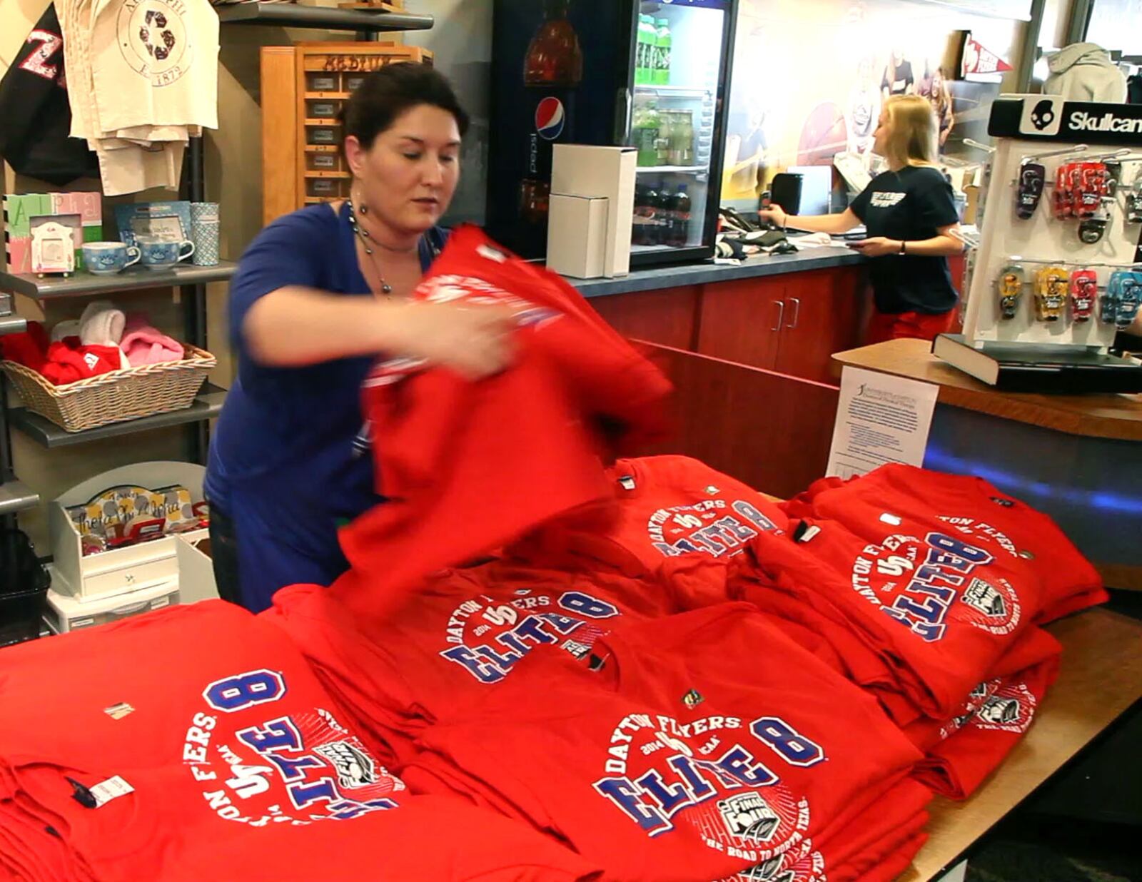 UD director of retail operations, Julie Banks, unboxes some of the 6,000 t-shirts printed for the University of Dayton Flyers return to the NCAA Elite Eight before being sold on Friday afternoon.  TY GREENLEES / STAFF