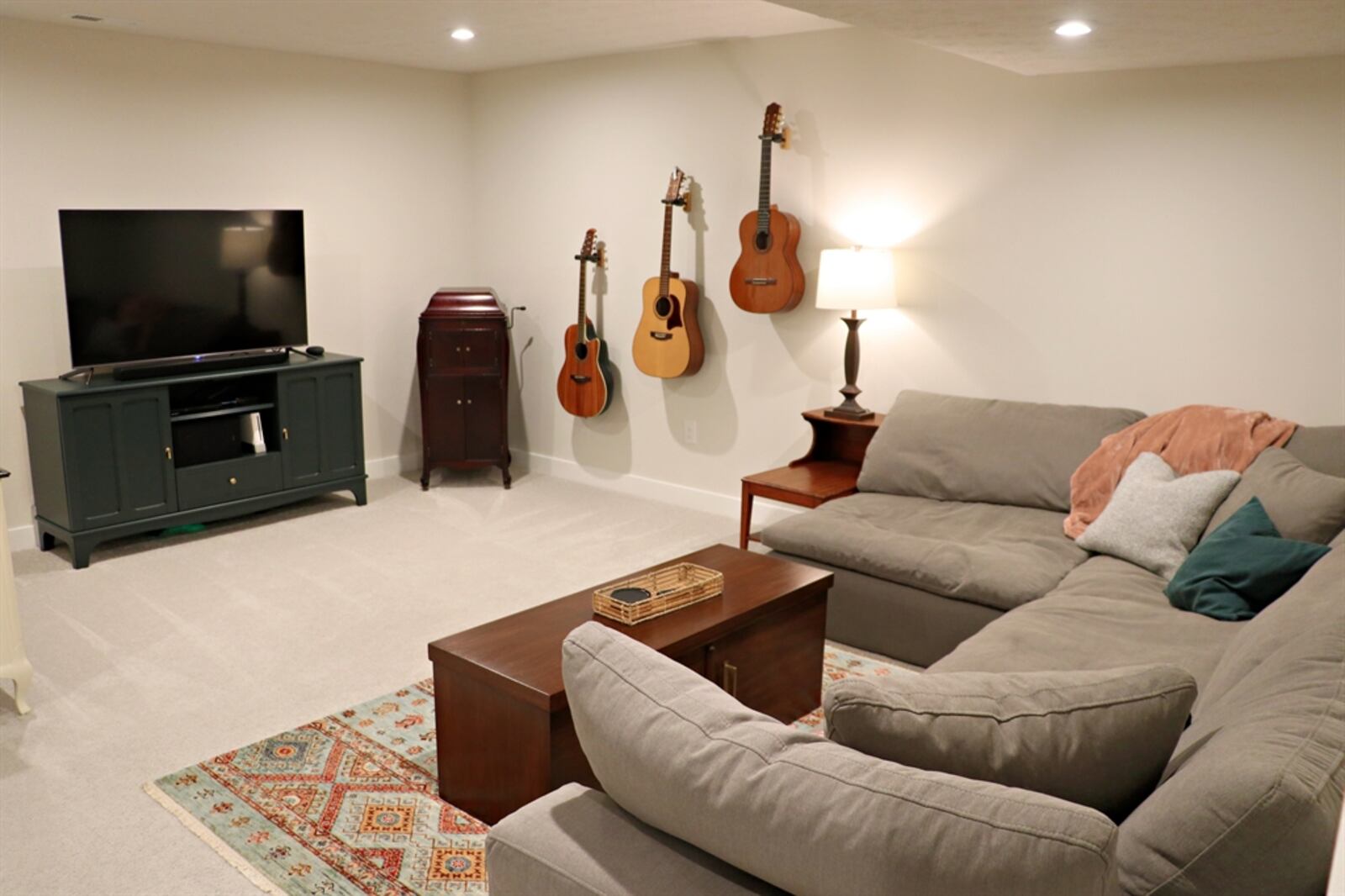 A spacious family room with a media area and ceiling lights is in the basement. 