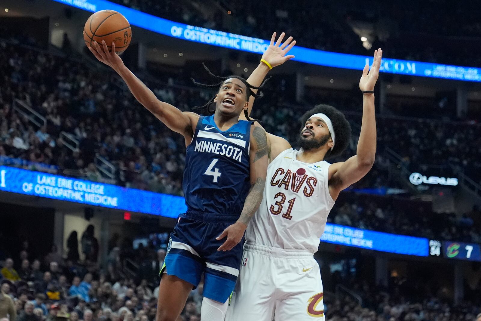 Minnesota Timberwolves guard Rob Dillingham (4) goes to the basket in front of Cleveland Cavaliers center Jarrett Allen (31) in the first half of an NBA basketball game Monday, Feb. 10, 2025, in Cleveland. (AP Photo/Sue Ogrocki)