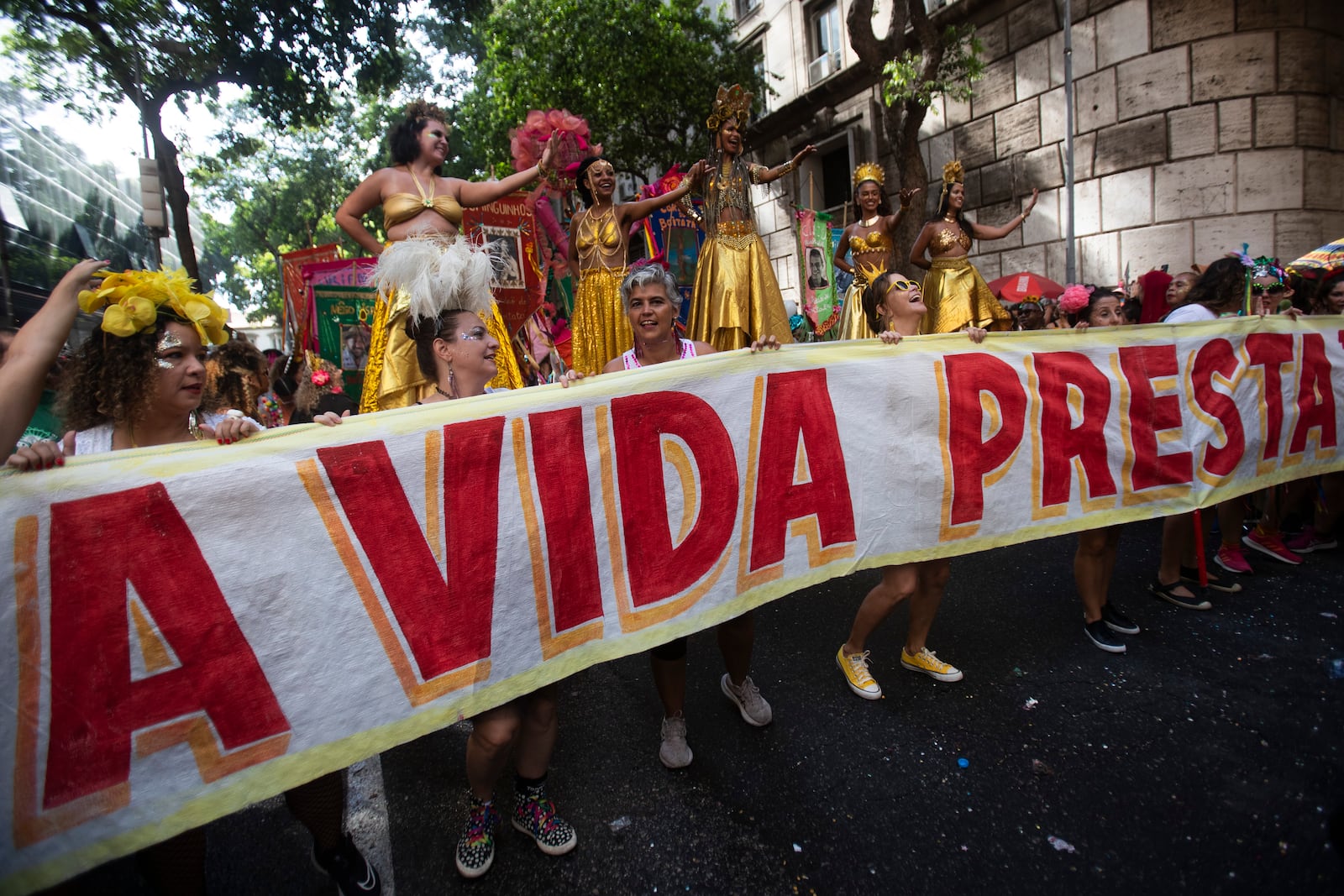 Revelers hold a banner that reads in Portuguese; "Life is worth it," in tribute to Brazilian actress Fernanda Torres, who's competing for the best actress Oscar for her role in "I'm Still Here", at the "Cordao do Boitata" street pre-carnival party in Rio de Janeiro, Sunday, Feb. 23, 2025. (AP Photo/Bruna Prado)