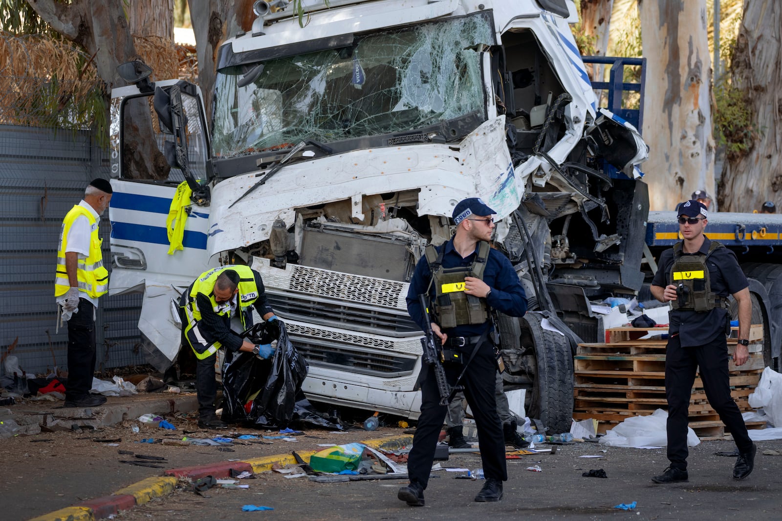 Israeli police and rescue services inspect the site where a truck driver rammed into a bus stop near an army base, wounding dozens of people, according to Israel's Magen David Adom rescue service in Ramat Hasharon, Israel, Sunday, Oct. 27, 2024. (AP Photo/Oded Balilty)