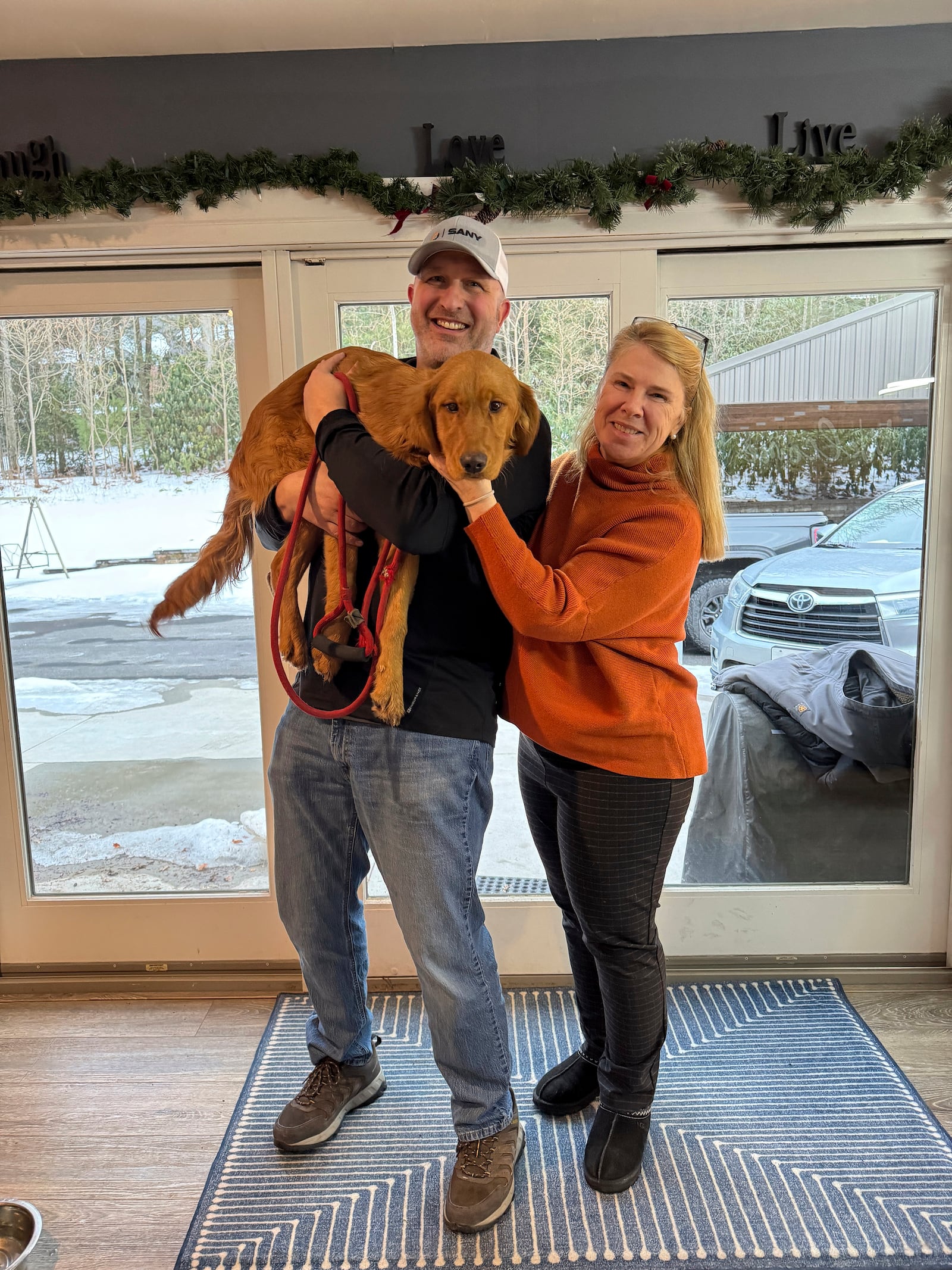 This Feb. 24 2025 photo provided by Dr, Carolyn Canizaro-Orlowsky, shows Joe and Pam Palko, after being reunited with their a six-month-old Golden retriever pup named Freddy, a week after the dog ran off from their home at the base of Sharp Mountain in Pottsville, Pa. (Dr, Carolyn Canizaro-Orlowsky photo via AP)