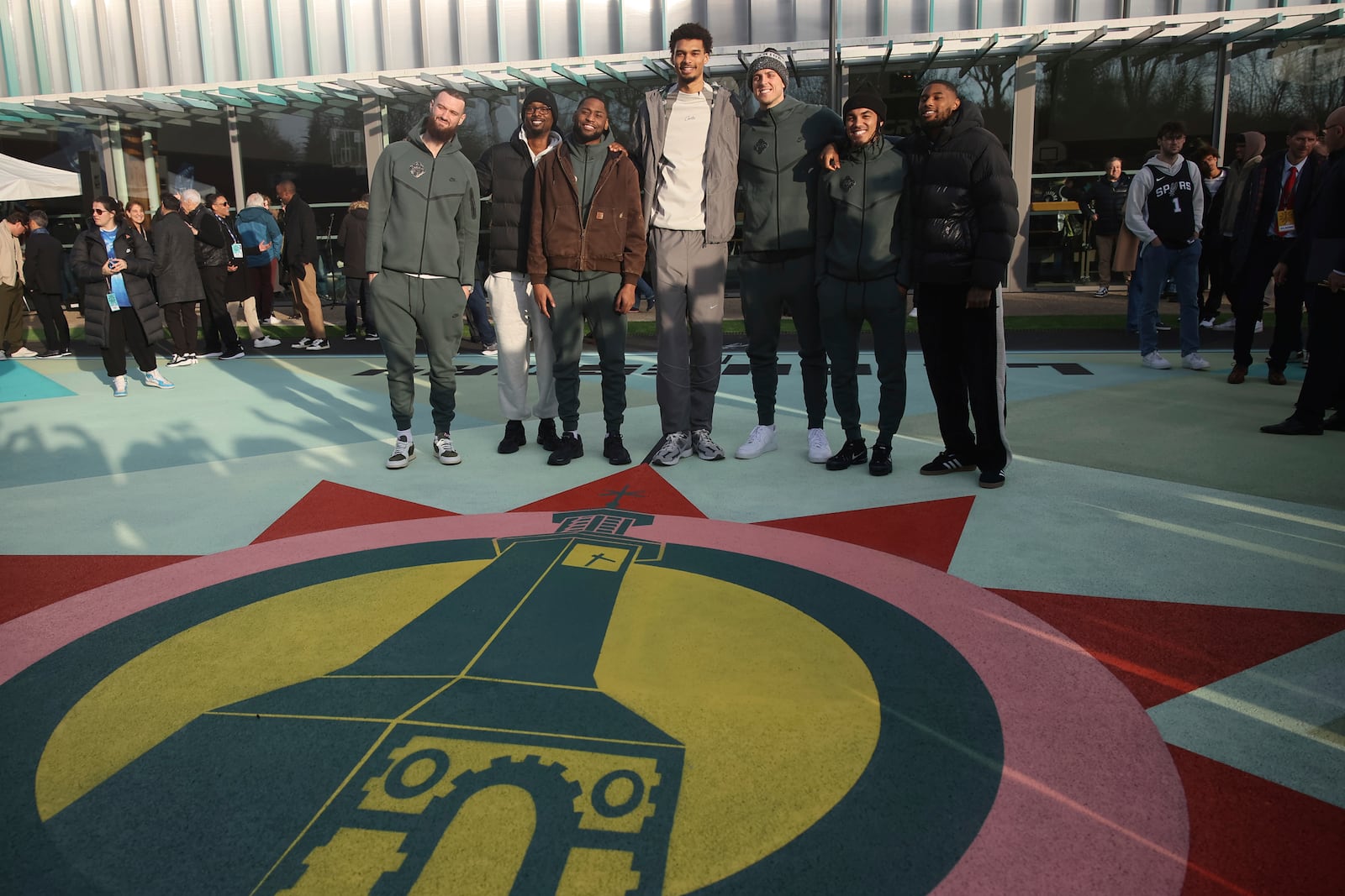 San Antonio Spurs' Victor Wembanyama, center, and teammates pose as he inaugurates a basketball court, Tuesday, Jan. 21, 2025 in Le Chesnay-Rocquencourt, south of Paris. (AP Photo/Thomas Padilla)