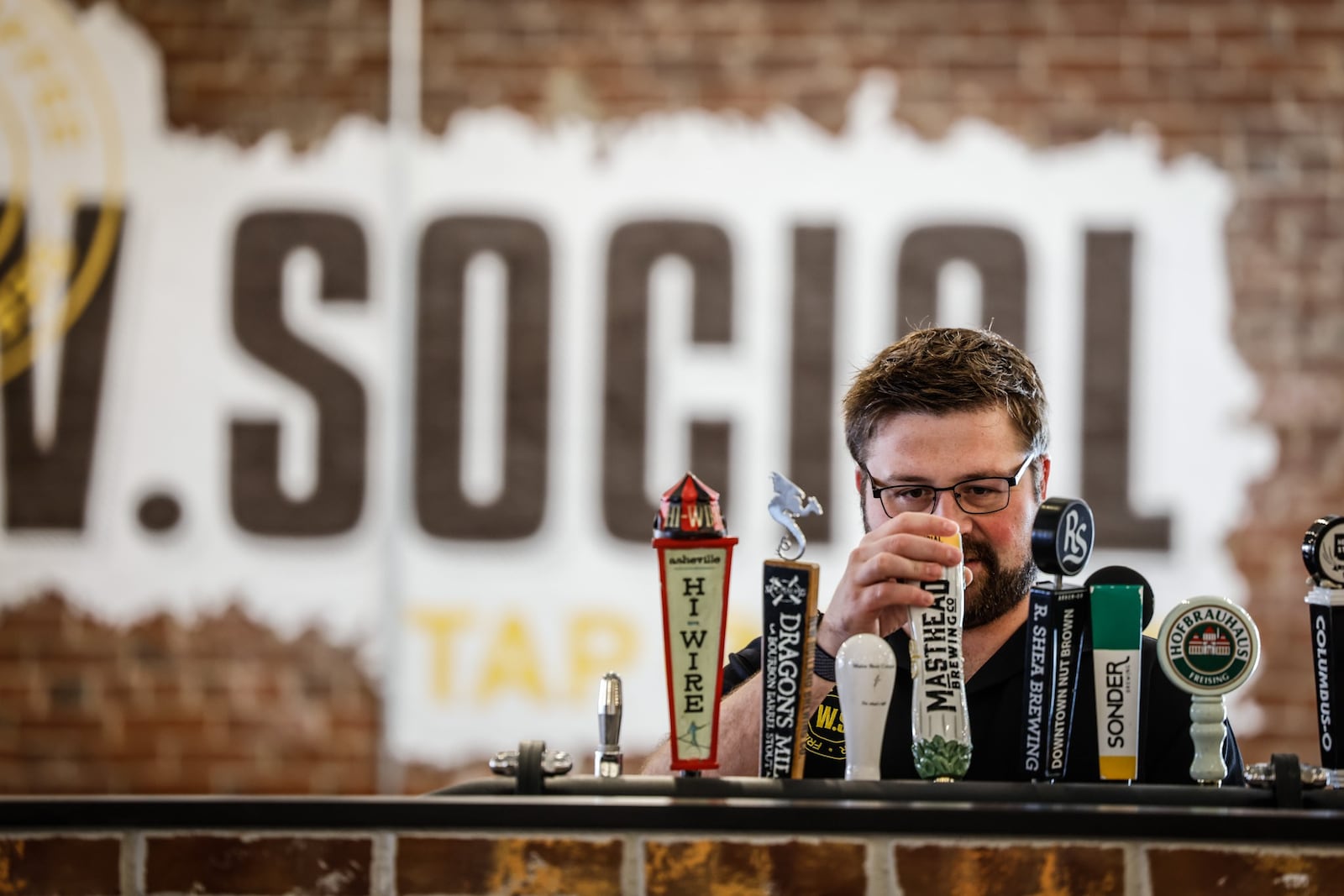 Rob Barry, general manager of West Social Tap and Table works on the beer taps at the bar. The food hall plans to open to the public July 25, 2022. JIM NOELKER/STAFF