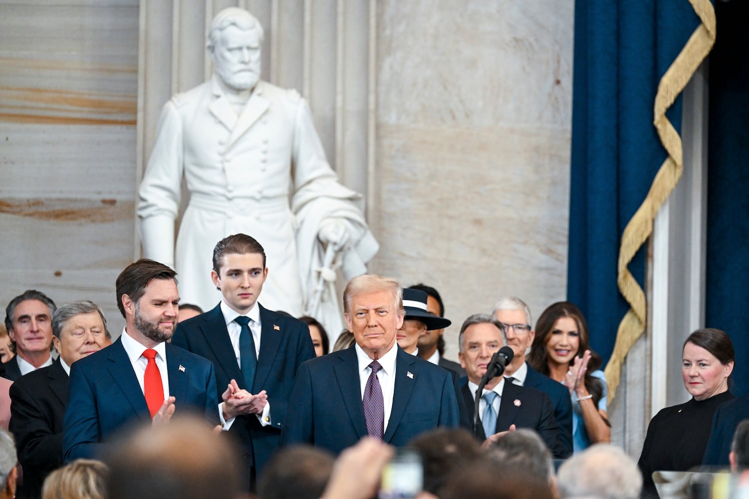 
                        President-elect Donald Trump, center, arrives at his inauguration as the 47th president in the Rotunda at the Capitol in Washington on Monday morning, Jan. 20, 2025. Vice President-elect JD Vance, left, and Barron Trump, second from left, applaud. (Kenny Holston/The New York Times)
                      