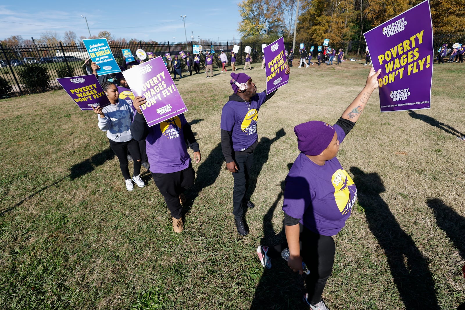 Airport workers wave signs as they march in front of the Charlotte Douglas International Airport in Charlotte, N.C., Monday, Nov. 25, 2024. (AP Photo/Nell Redmond)