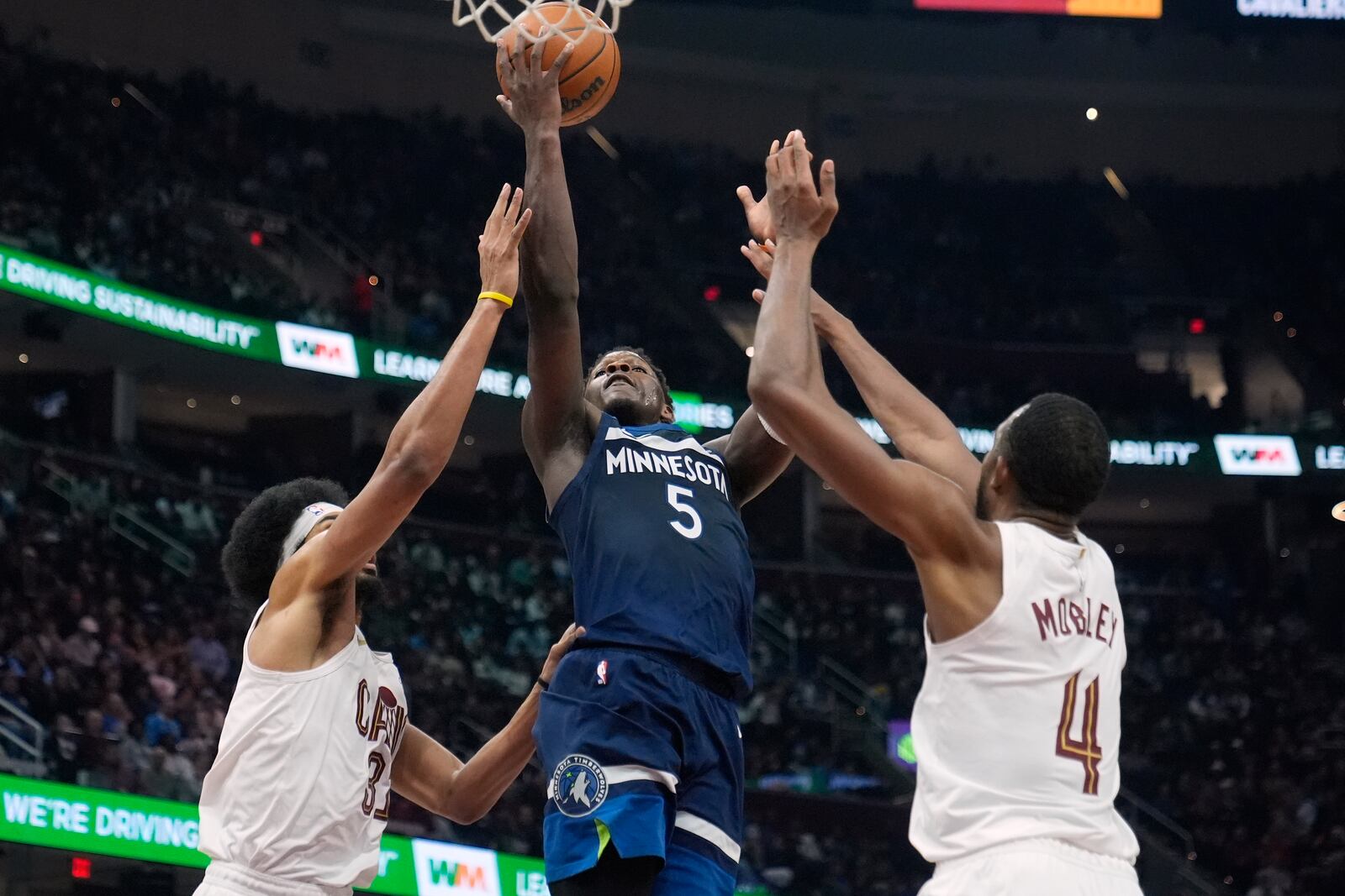 Minnesota Timberwolves guard Anthony Edwards (5) shoots between Cleveland Cavaliers center Jarrett Allen (31) and forward Evan Mobley (4) in the first half of an NBA basketball game Monday, Feb. 10, 2025, in Cleveland. (AP Photo/Sue Ogrocki)