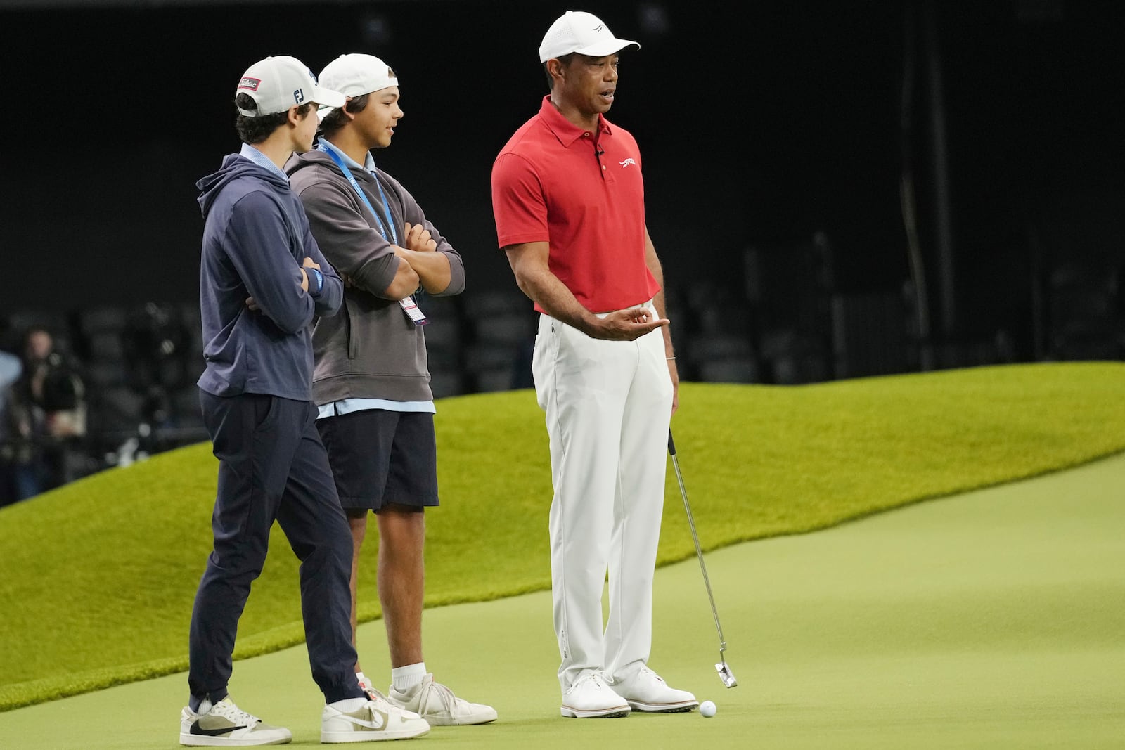 Tiger Woods, right, talks to his son Charlie and a friend while he warms up before a match between Los Angeles Golf Club and his Jupiter Links Golf Club, Tuesday, Jan. 14, 2025, in Palm Beach Gardens, Fla. (AP Photo/Marta Lavandier)