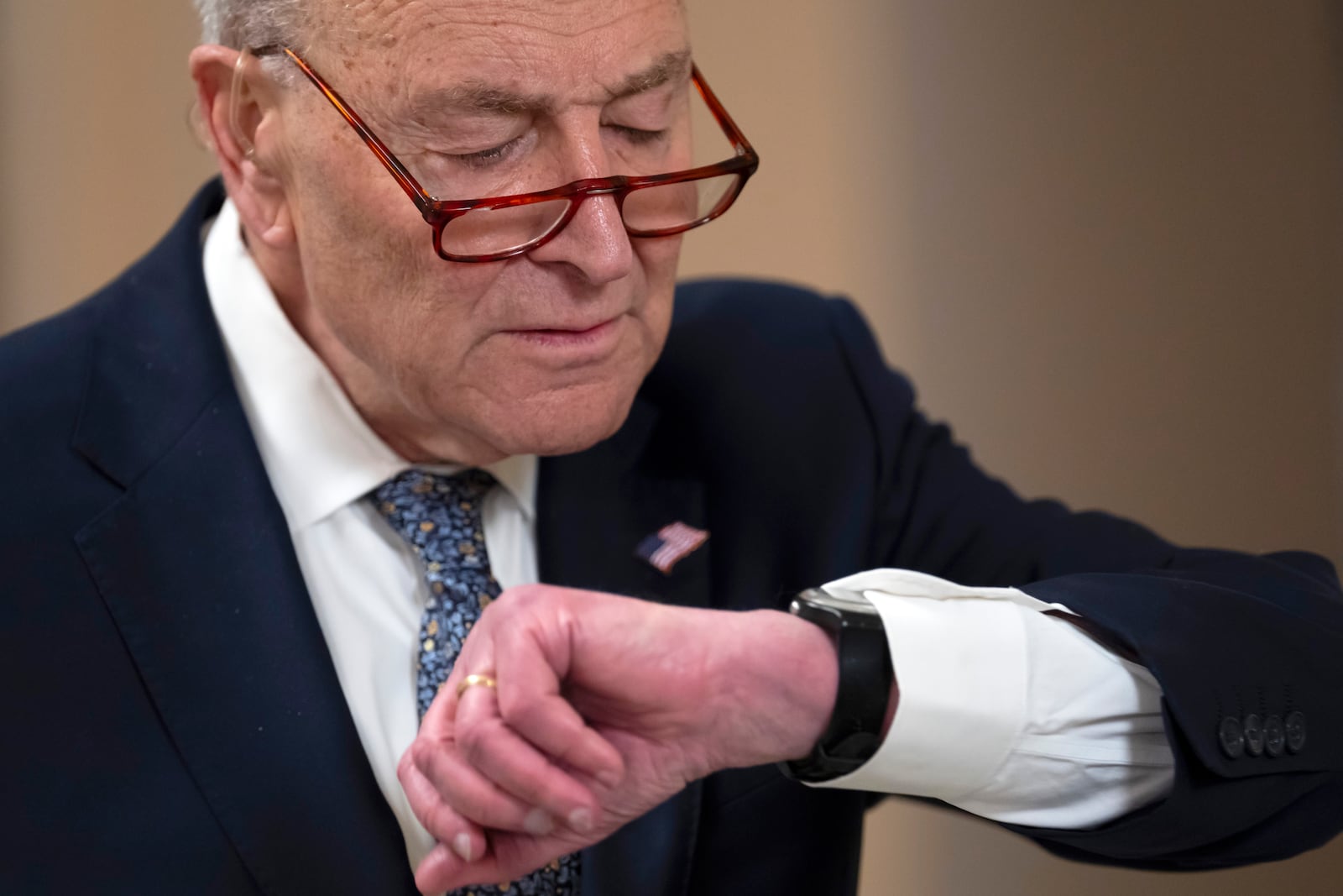 Senate Minority Leader Chuck Schumer, D-N.Y., looks at his watch before a television interview as the Senate works to avert a partial government shutdown ahead of the midnight deadline, at the Capitol in Washington, Friday, March 14, 2025. (AP Photo/Ben Curtis)