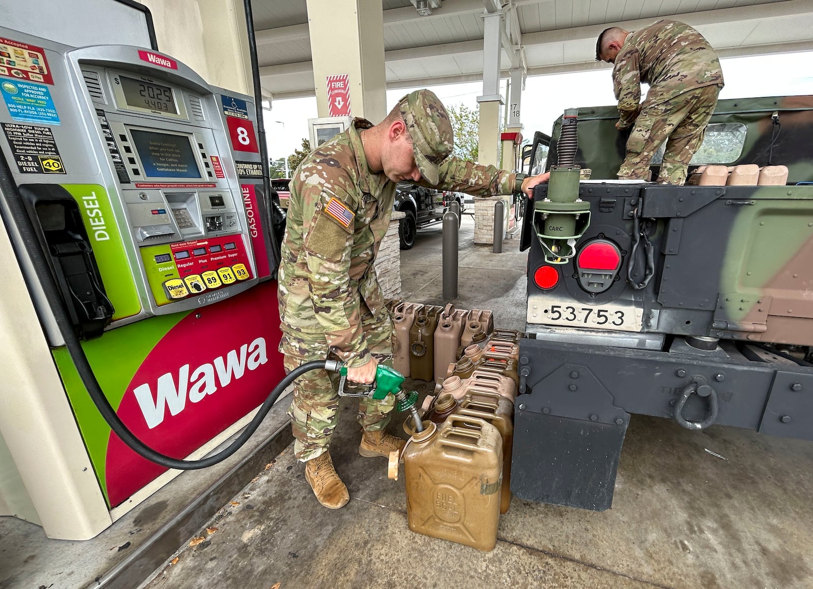 National Guardsmen, who asked not to be identified, fill gas cans at a Wawa gas station, Tuesday, Sept. 27, 2022, in Pinellas Park, Fla., as Florida's west coast prepares for Hurricane Ian. (Chris Urso/Tampa Bay Times via AP)