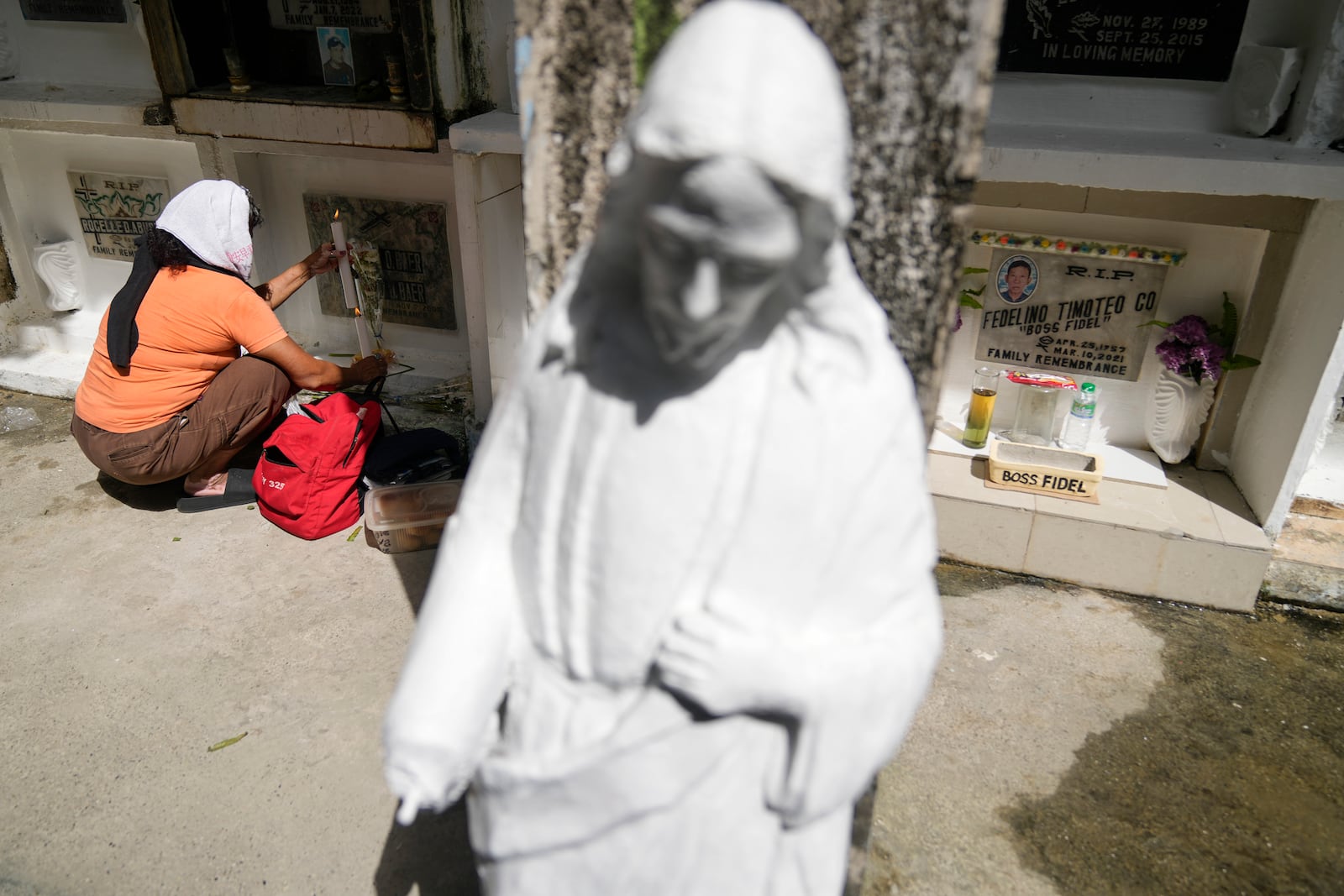 Gloria Obrado Baer lights candles at the tomb of her brother at Manila's North Cemetery, Philippines as the nation observes All Saints Day on Friday, Nov. 1, 2024. (AP Photo/Aaron Favila)