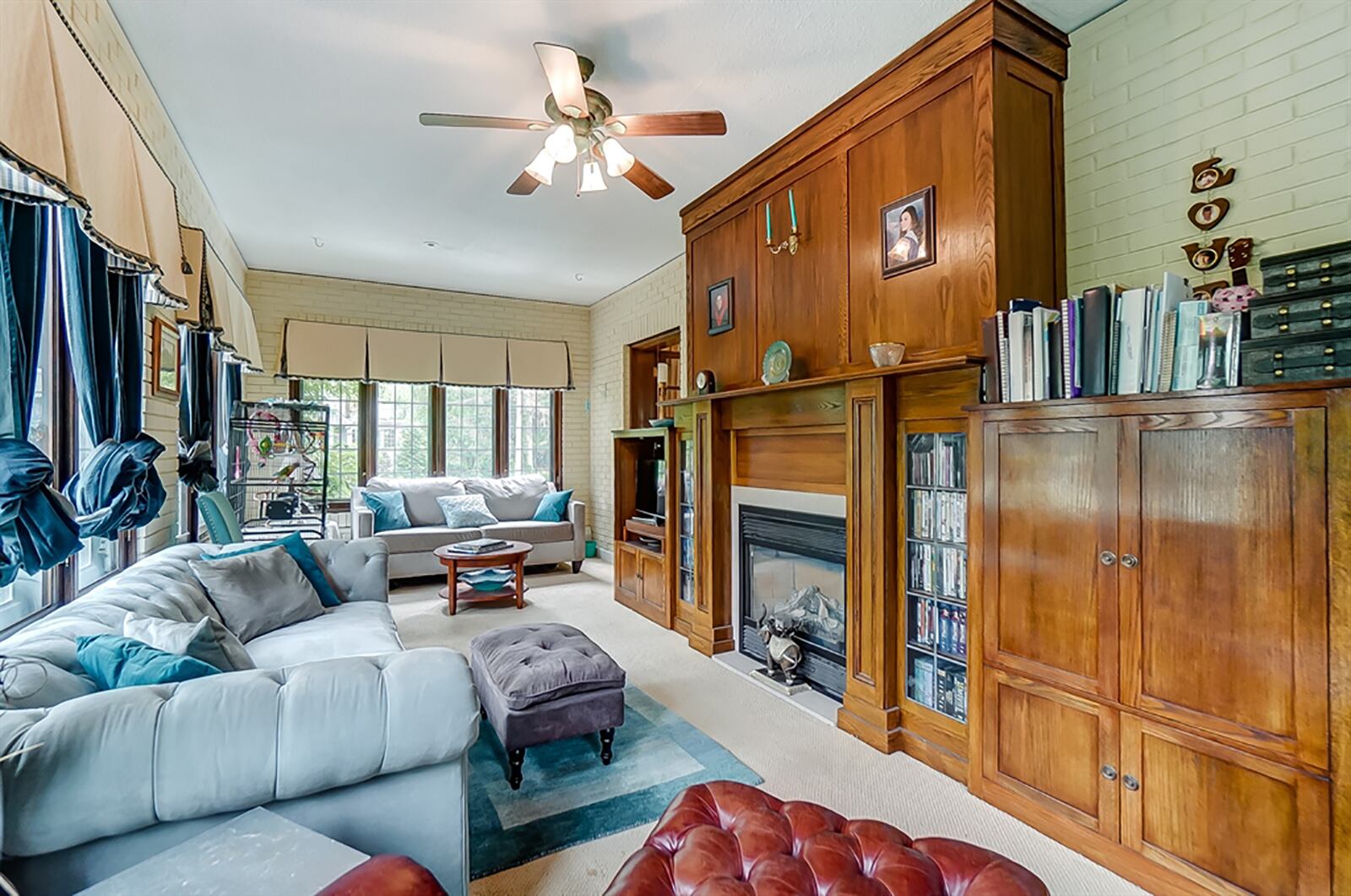 Two sets of French doors open into a sunroom, which has a wall of built-ins to allow for flexible floor plan options. The built-ins include leaded-glass bookcases that flank a gas fireplace and cabinetry with pull-out shelves. CONTRIBUTED PHOTO