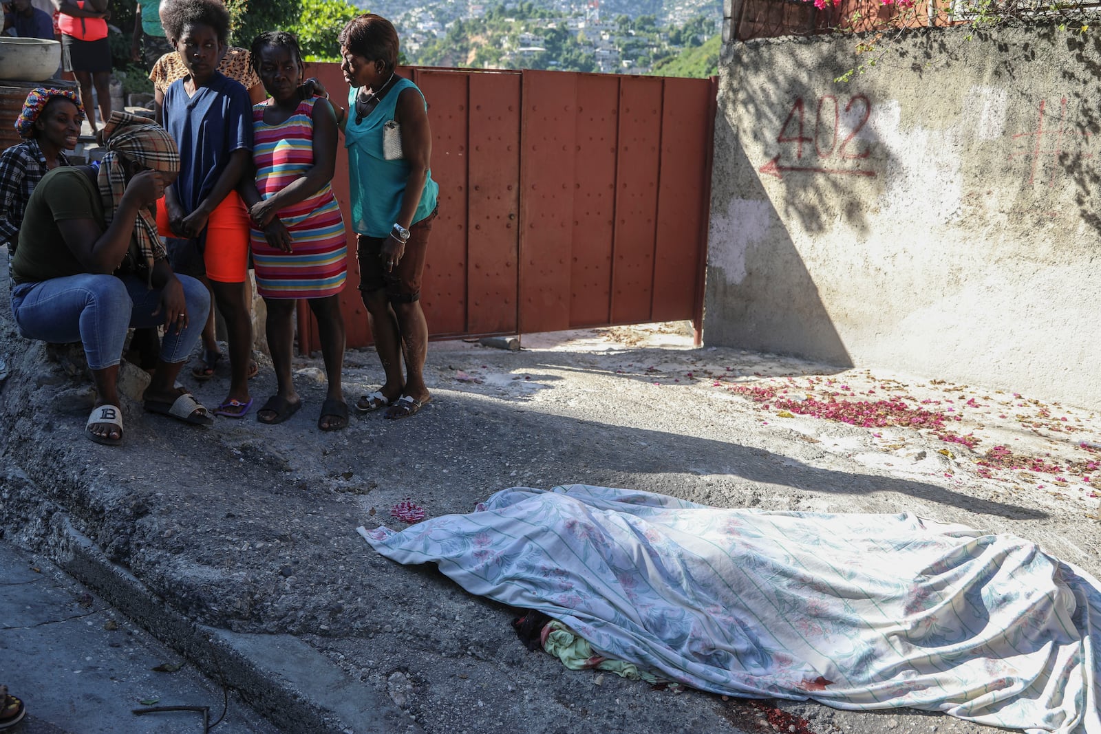 Residents gather before a person they say was killed in an attack by gang members, in the Pétion-Ville neighborhood of Port-au-Prince, Haiti, Tuesday, Nov. 19, 2024. (AP Photo/Odelyn Joseph)