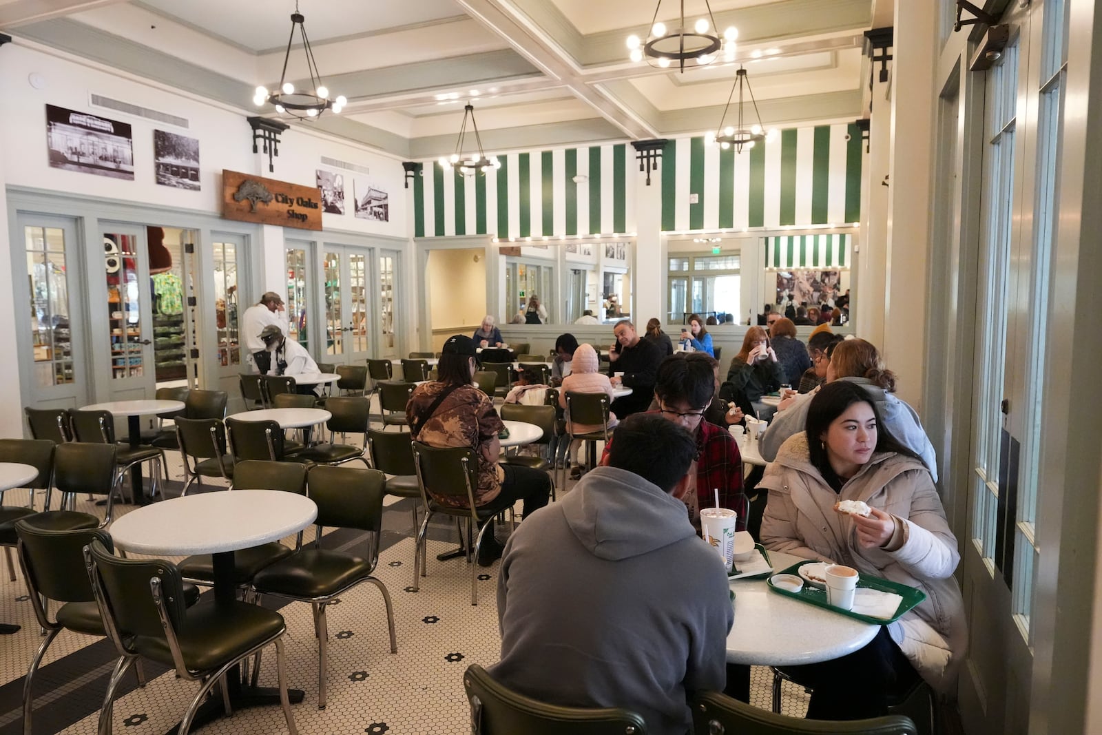 Patrons enjoy beignets and cafe au lait in Cafe du Monde in City Park in New Orleans, Friday, Jan. 24, 2025. (AP Photo/Gerald Herbert)