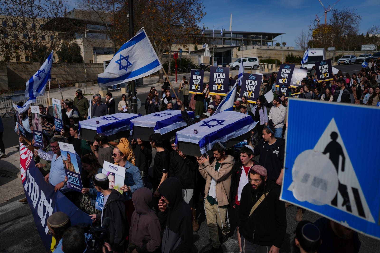 Activists representing families of Israelis killed during the war in Gaza carry mock coffins covered with Israeli flags that are meant to symbolize the price Israel will pay for agreeing to a ceasefire with Hamas in a demonstration against the deal , in Jerusalem on Thursday, Jan. 16, 2025. (AP Photo/Ohad Zwigenberg)