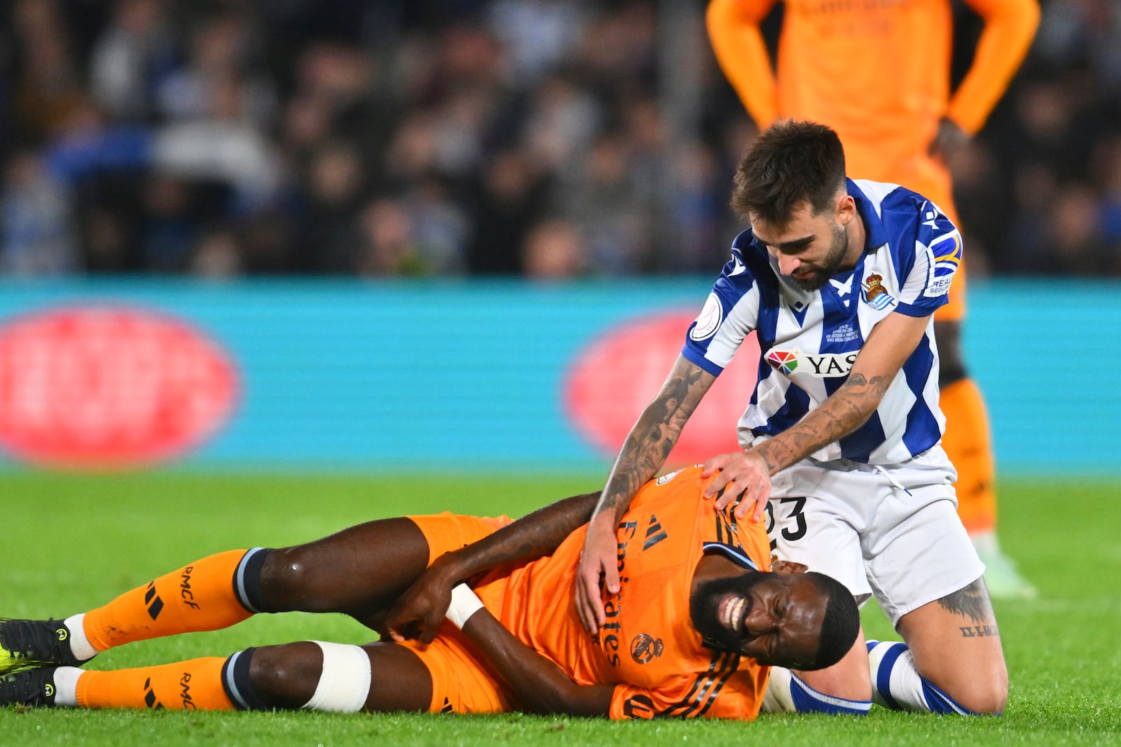 Real Sociedad's Brais Mendez, right, comforts Real Madrid's Antonio Rudiger during the Spanish Copa del Rey soccer match between Real Sociedad and Real Madrid at the Reale Arena in San Sebastian, Spain, Wednesday, Feb. 26, 2025. (AP Photo/Miguel Oses)