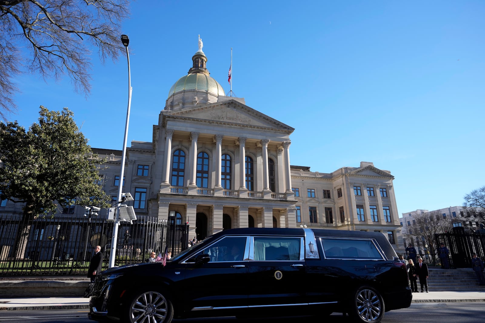 The hearse carrying the flag-draped casket of former President Jimmy Carter pauses outside the State Capitol in Atlanta, Saturday, Jan. 4, 2025. Carter died Dec. 29 at the age of 100. (AP Photo/Alex Brandon, Pool)