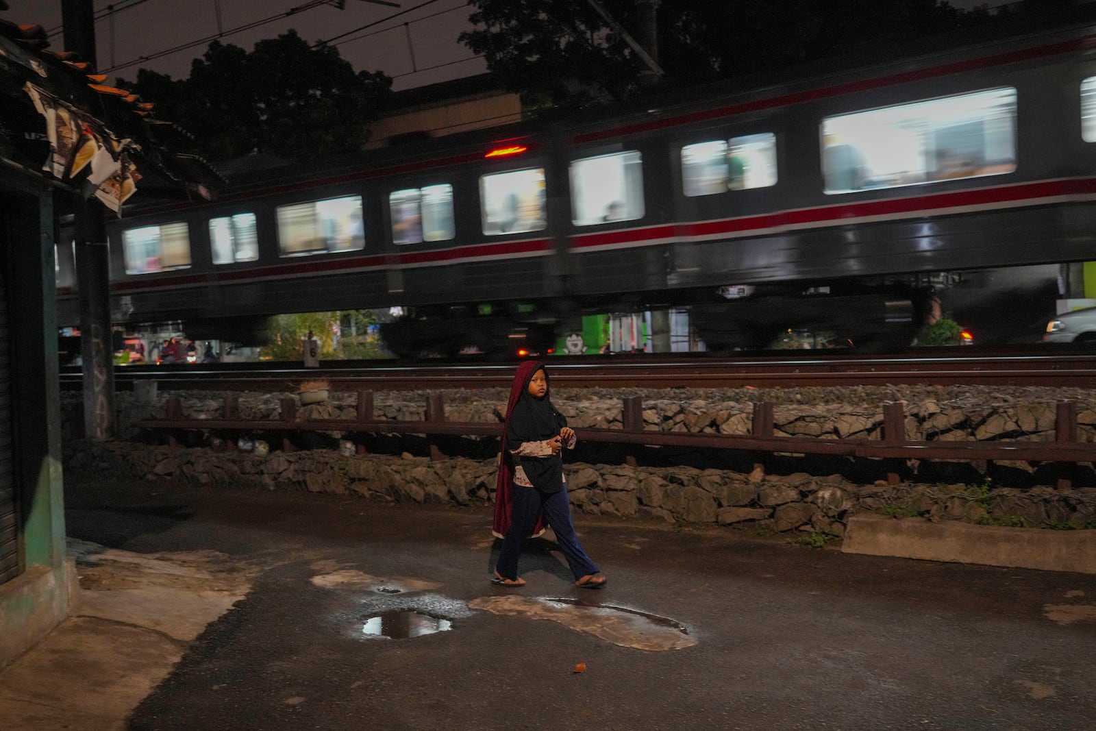 A young girl walks next to a railway track near the scene of a 1987 train collision that killed 139 people in Bintaro, Indonesia, Friday, Oct. 25, 2024. (AP Photo/Tatan Syuflana)