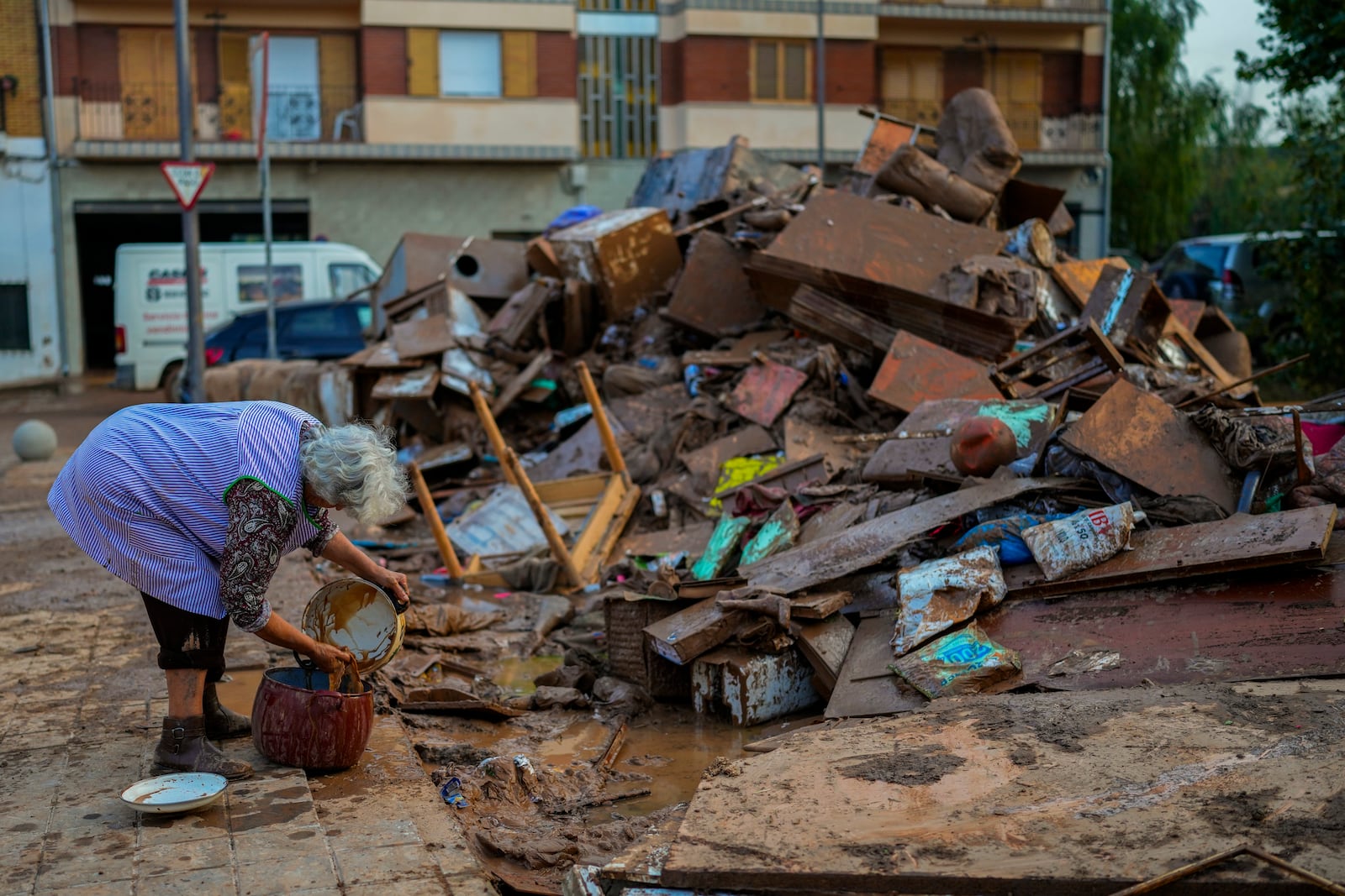 A woman cleans her house affected by floods in Utiel, Spain, Wednesday, Oct. 30, 2024. (AP Photo/Manu Fernandez)