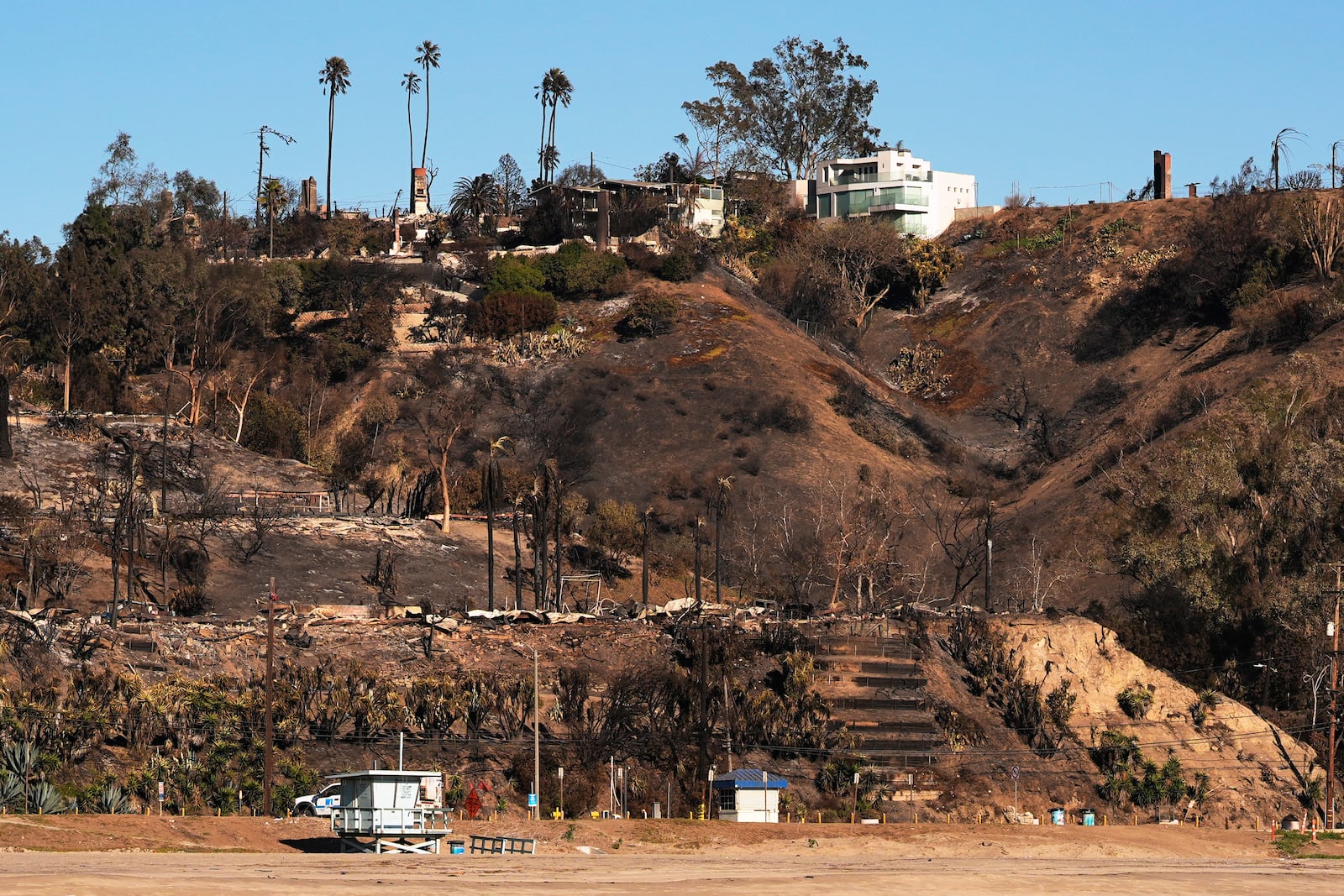 Properties are damaged by the Palisades Fire in the Pacific Palisades neighborhood of Los Angeles, Wednesday, Jan. 15, 2025. (AP Photo/Carolyn Kaster)