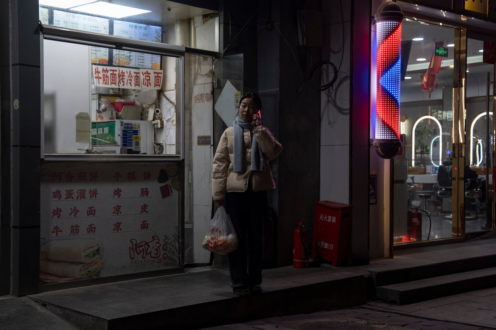 A woman makes a phone call while shopping for food ahead of the National People's Congress in Beijing, on Feb. 26, 2025. (AP Photo/Ng Han Guan)