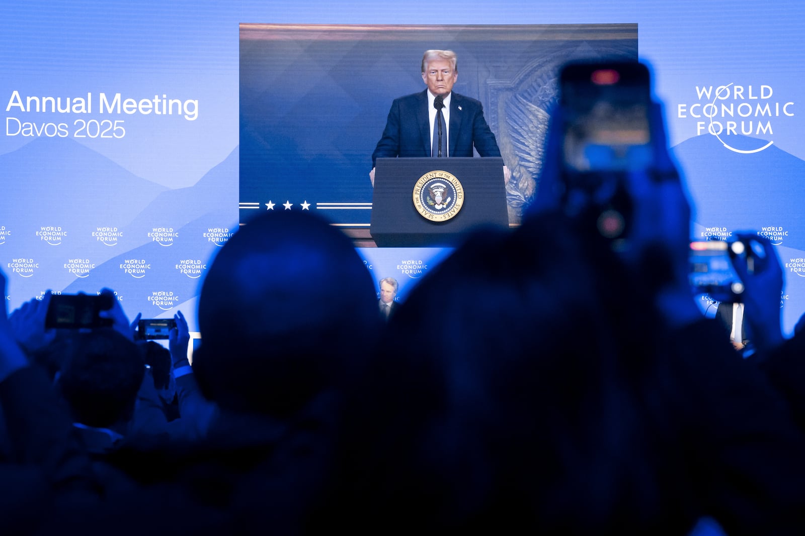 US President Donald J. Trump is shown on screens as he addresses via remote connection a plenary session in the Congress Hall, during the 55th annual meeting of the World Economic Forum (WEF), in Davos, Switzerland, Thursday, Jan. 23, 2025. (Michael Buholzer/Keystone via AP)