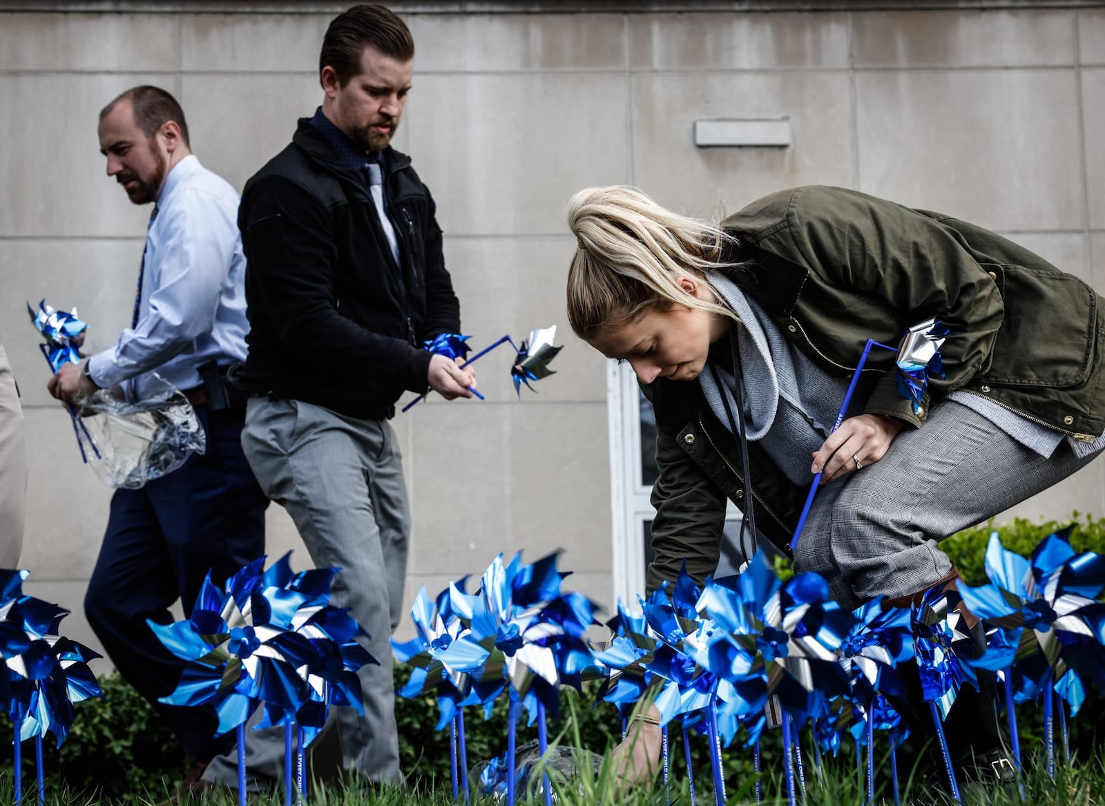 Dayton police Special Victims Unit detectives from left, Doug Thompson, Josh Bowling and Karina Sulek plant a pinwheel garden in front of the Safety Building on West Third St. in honor of Child Abuse Prevention Month. JIM NOELKER/STAFF