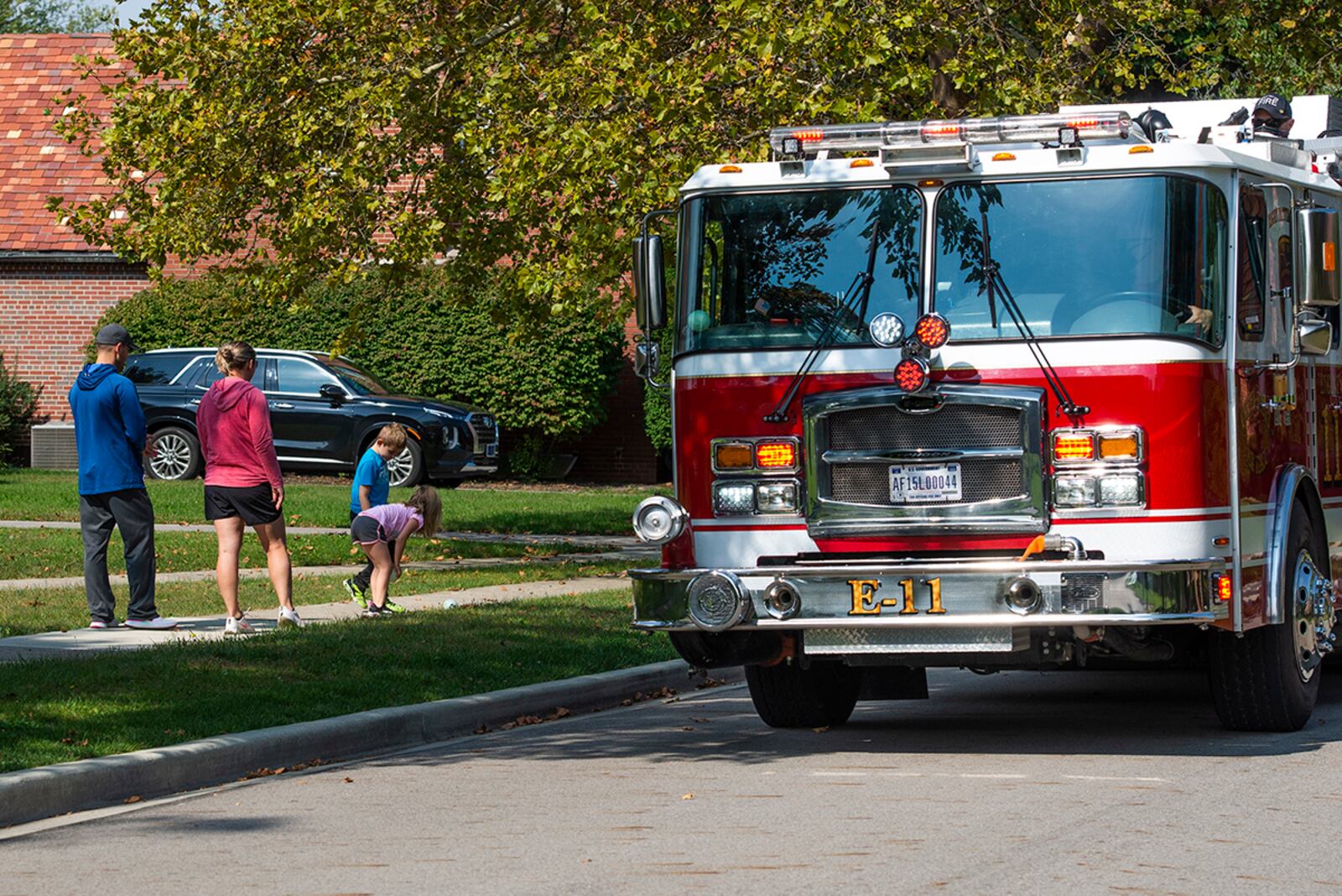 Brick Quarters residents watch as the 788th Civil Engineer Squadron Fire Department holds a fire truck parade through military housing Oct. 2 to kick off Fire Prevention Week at Wright-Patterson Air Force Base. During the parade, firefighters threw out Frisbee rings, along with mini footballs and basketballs, for kids to enjoy. U.S. AIR FORCE PHOTO/WESLEY FARNSWORTH