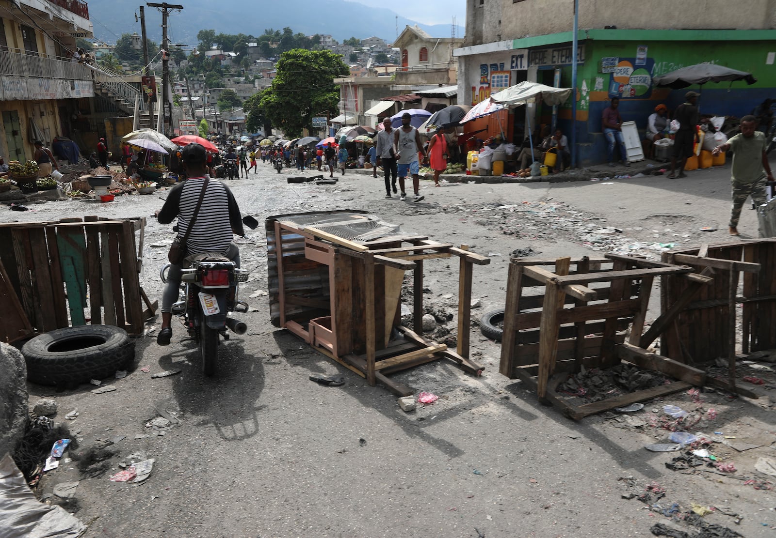 A motorcycle taxi driver crosses a barricade set up by residents, in Port-au-Prince, Haiti, Thursday, Nov. 14, 2024. (AP Photo/Odelyn Joseph)