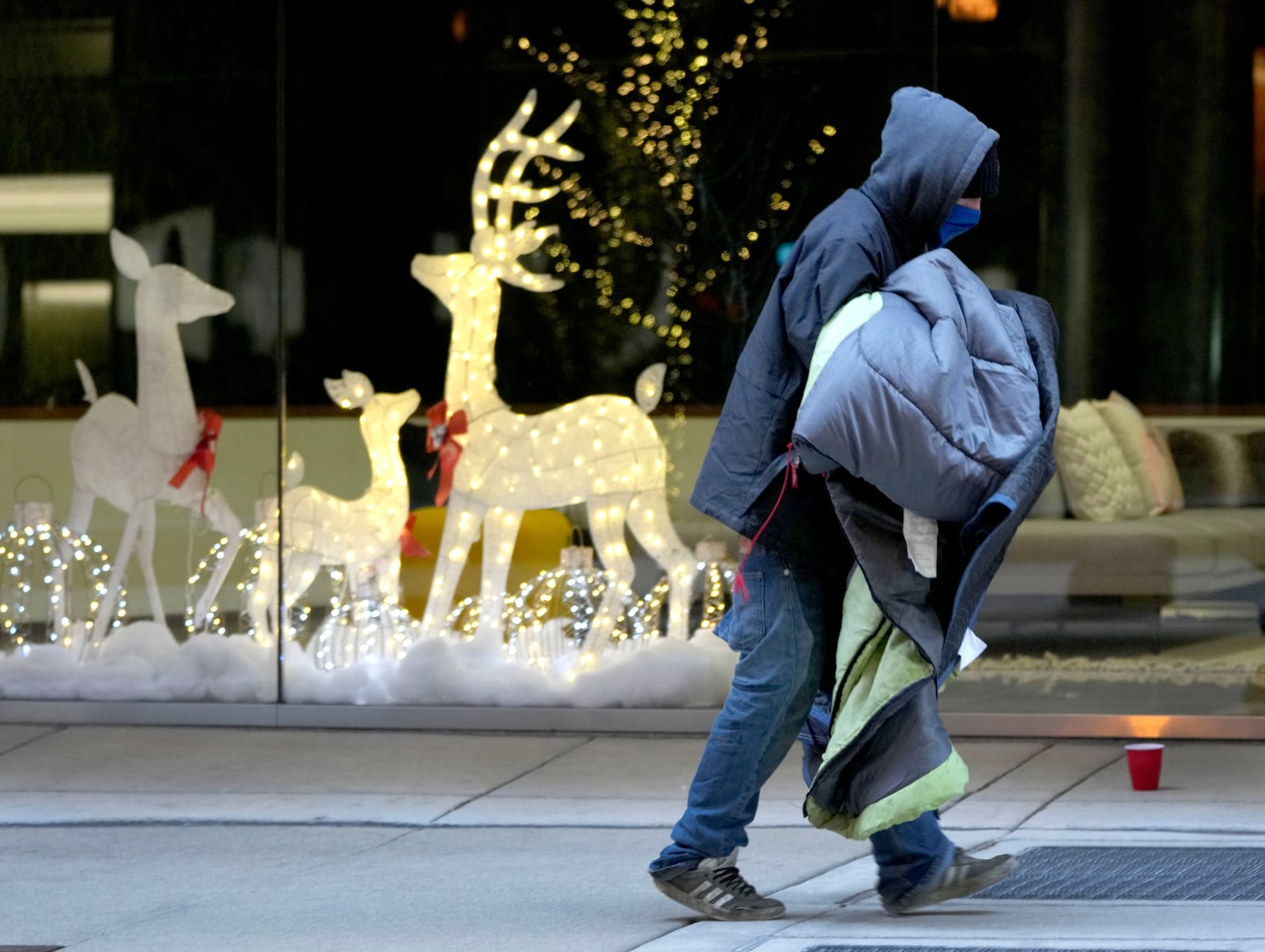 A man carries blankets as an Arctic blast brings single-digit temperatures with wind chills below zero on Thursday, Dec. 12, 2024, in Chicago. (AP Photo/Charles Rex Arbogast)