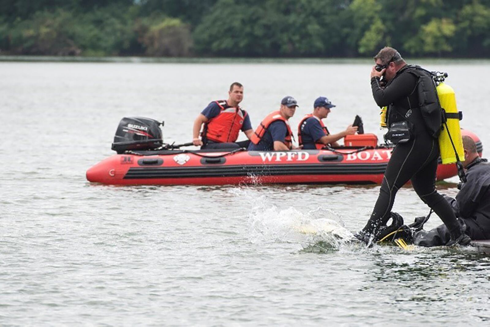 A diver from the 788th Civil Engineer Squadron Fire Department steps into the water to search for a reported drowning subject as part of a base exercise at Wright-Patterson Air Force Base July 31, 2018. Approximately a quarter of the base firefighters are dive qualified as the department is responsible for water rescue for several lakes on base and a portion of the Mad River. U.S. AIR FORCE PHOTO/WESLEY FARNSWORTH