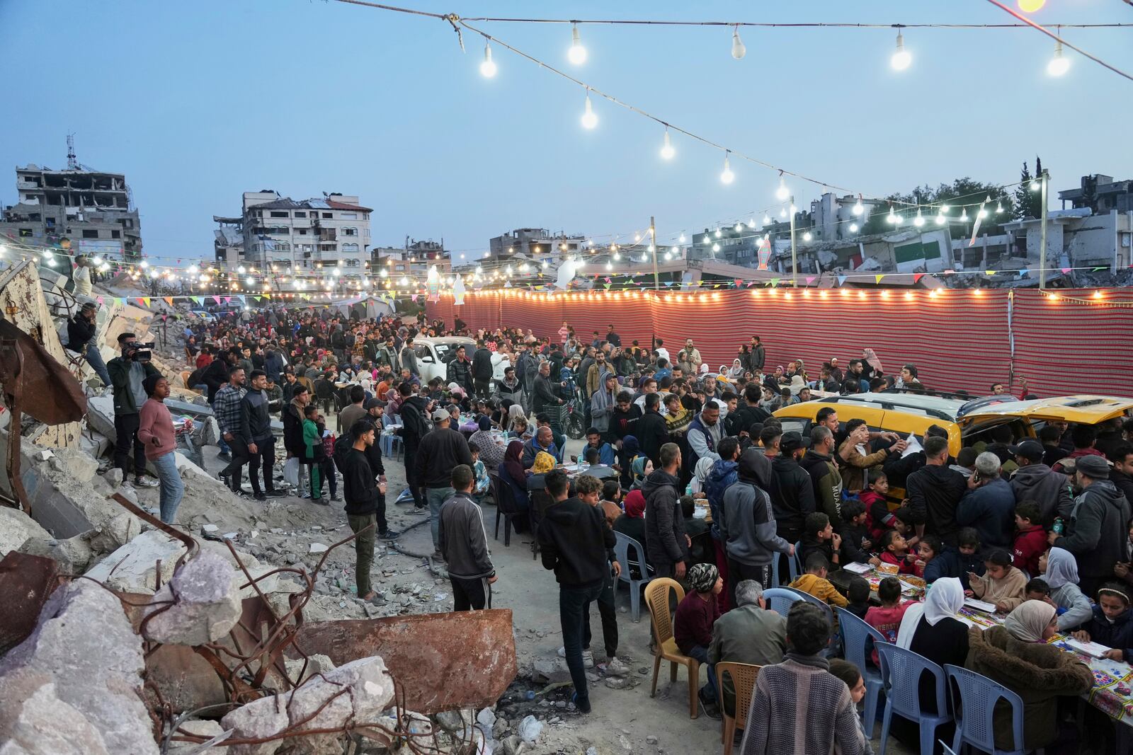 Palestinians sit at a large table surrounded by the rubble of destroyed homes and buildings as they gather for iftar, the fast-breaking meal, during Ramadan in Gaza City, Thursday March 6, 2025 (AP Photo/Abdel Kareem Hana)