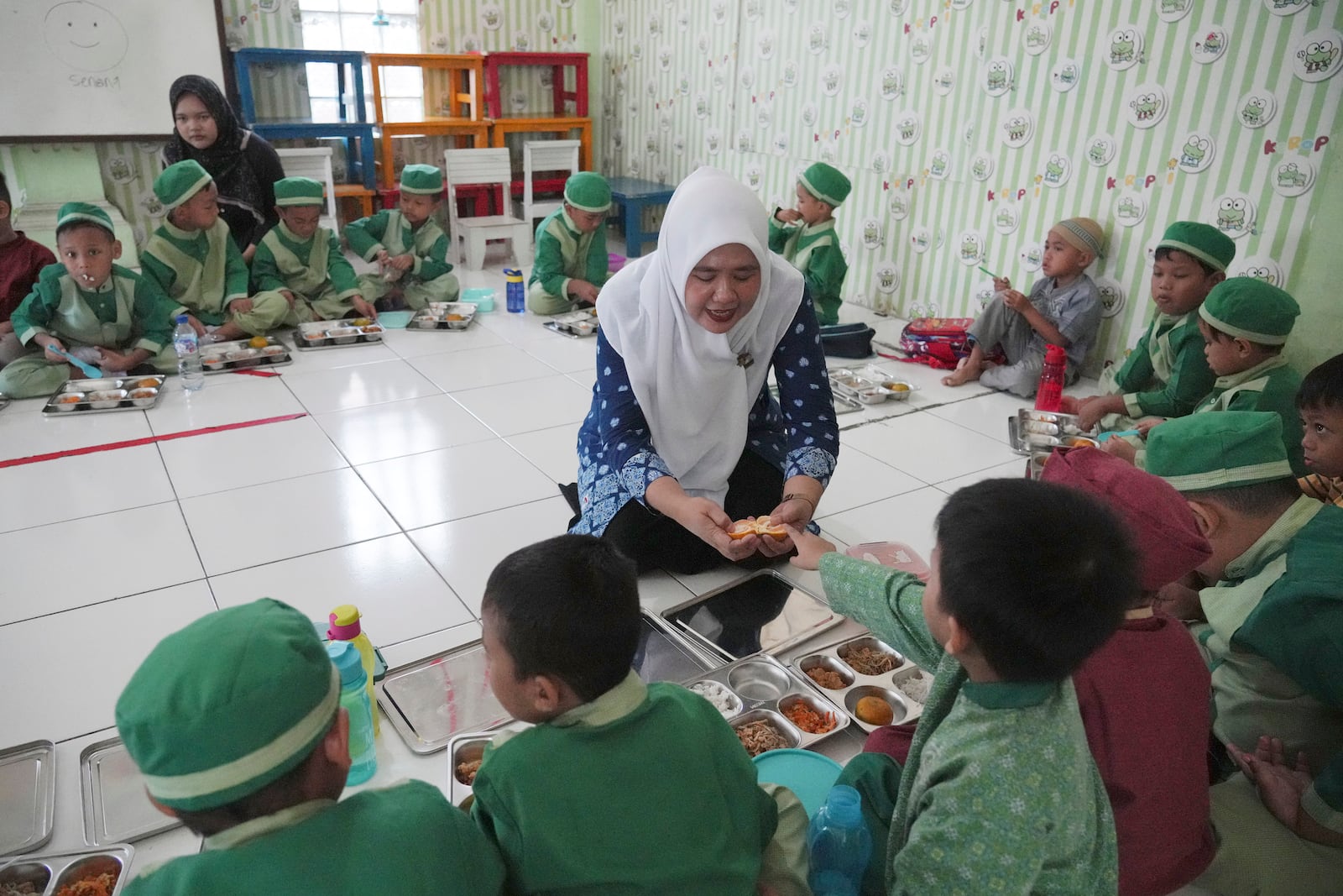 Students sit on the floor as they have their meals during the kick off of President Prabowo Subianto's ambitious free meal program to feed children and pregnant women nationwide despite critics saying that its required logistics could hurt Indonesia's state finances and economy at Early Childhood Education and Development in Jakarta, Indonesia, Monday, Jan. 6, 2025. (AP Photo/Achmad Ibrahim)