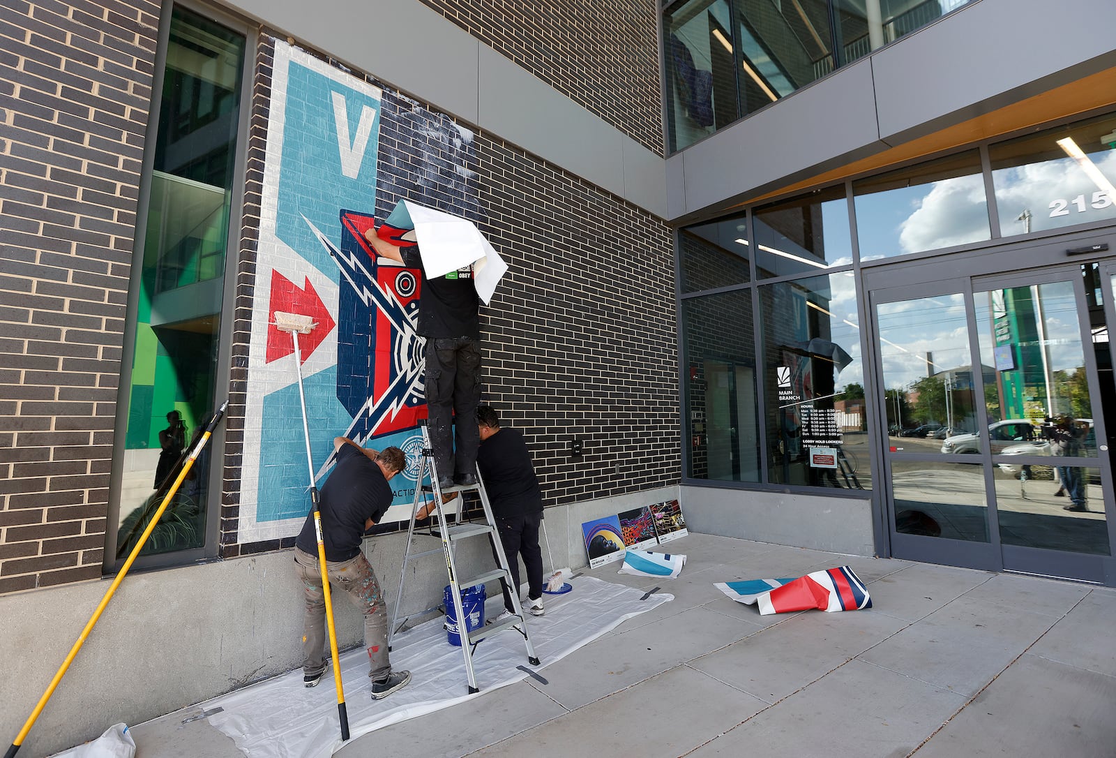 Muralist Shepard Fairey, places a mural Wednesday 18, 2024 on the Dayton Metro Library Downtown. MARSHALL GORBY\STAFF