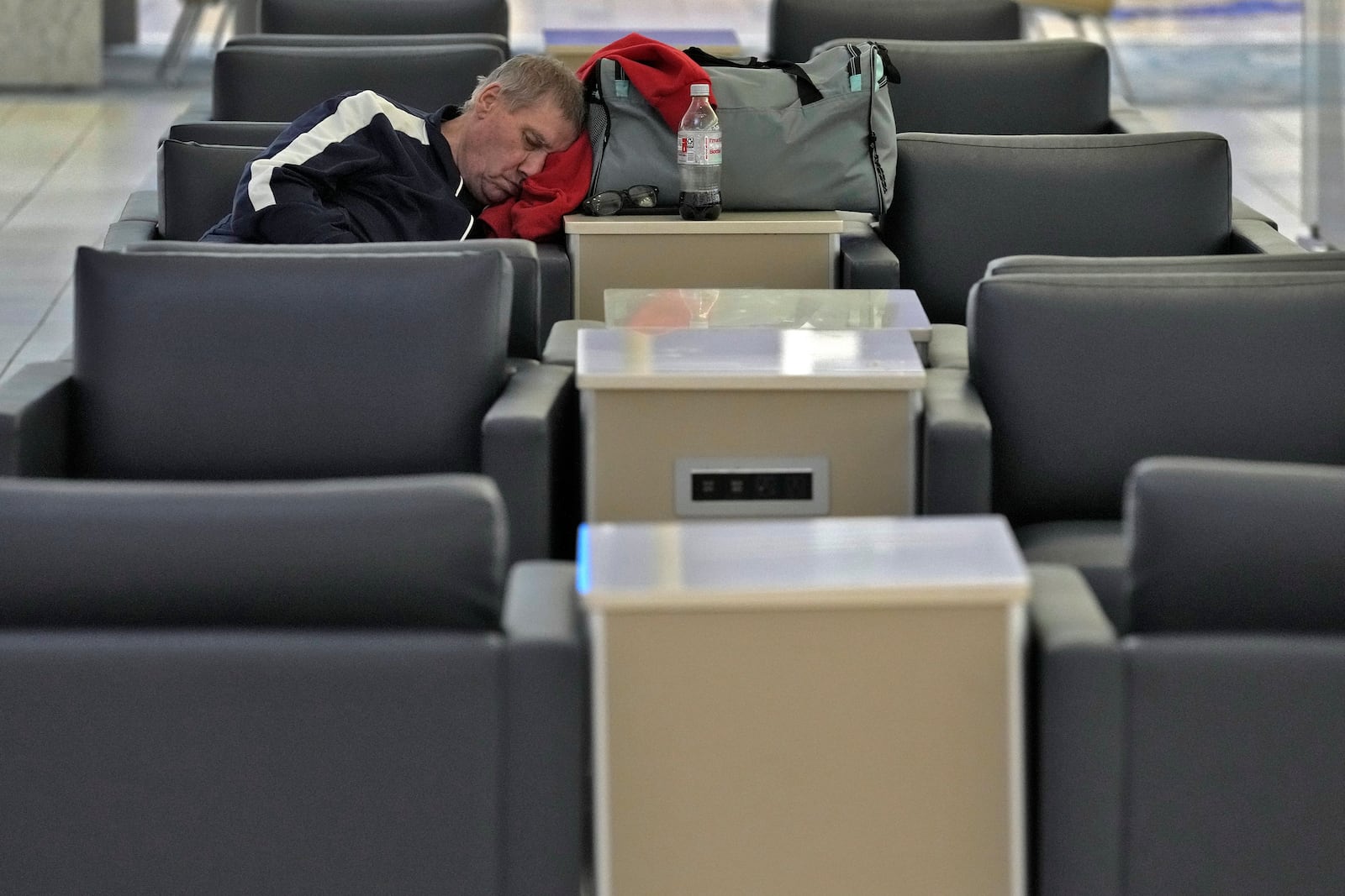 A passenger sleeps at the Tampa International Airport Tuesday, Oct. 8, 2024, in Tampa, Fla., after most flights were canceled due to the possible arrival of Hurricane Milton. (AP Photo/Chris O'Meara)