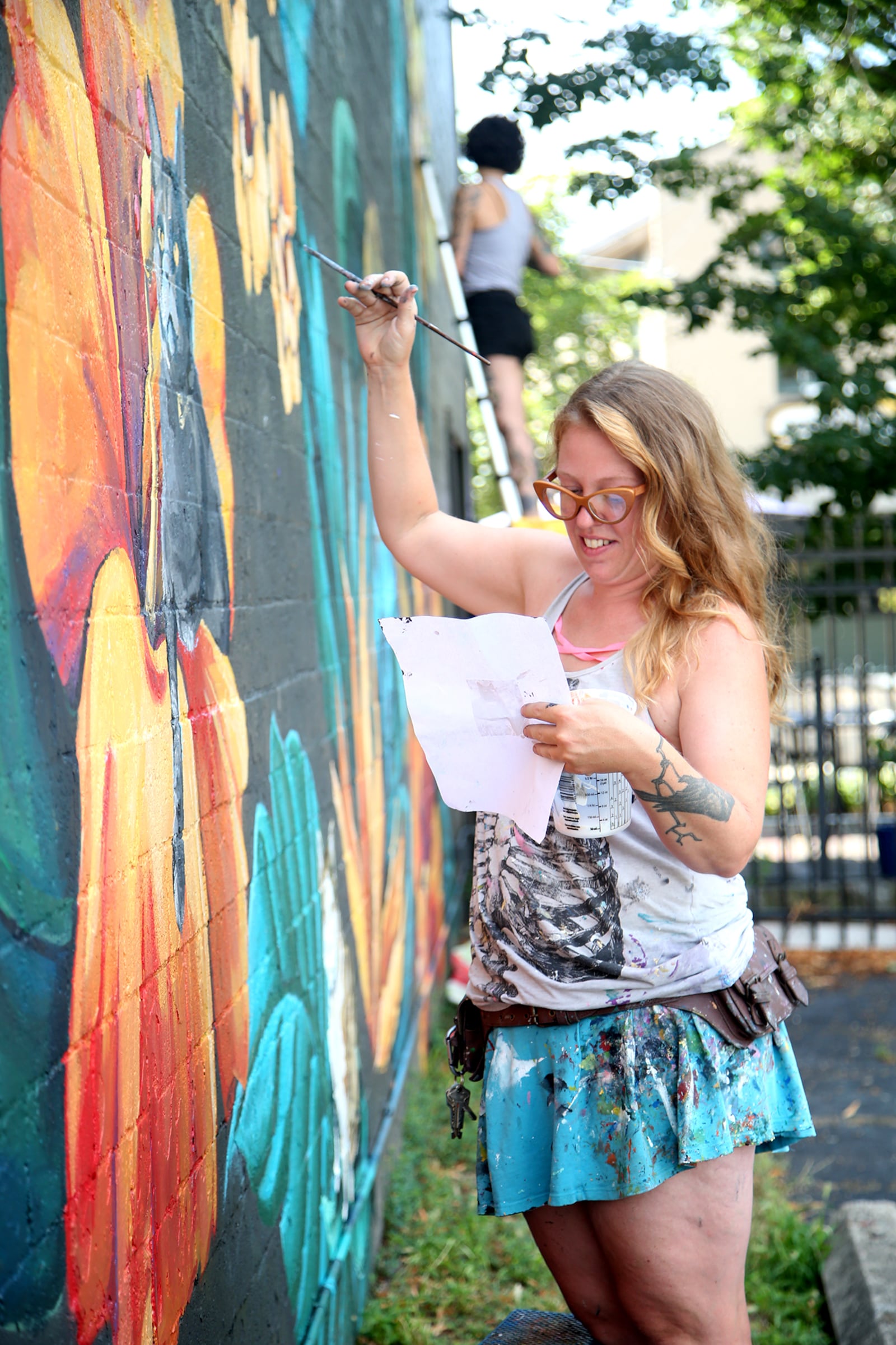 Tiffany Clark of the Mural Machine is creating a mural of cats on the side of Lilyâs Bistro in Daytonâs Oregon District. People who pay a fee will be able to submit pictures of their cats for realistic paintings on the west side of the restaurant. The project is a fundraiser for local groups dedicated to animal welfare. So far 40 cats are committed to the project and there is room for 85 feline portraits.  LISA POWELL / STAFF