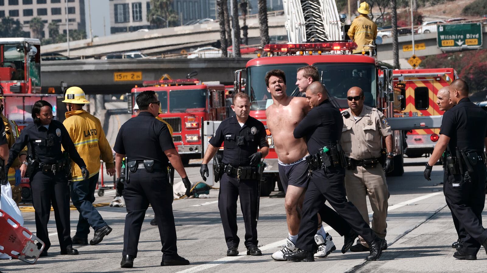 Los Angeles police officer arrest a man after he jumped from a freeway sign onto a safety airbag in downtown Los Angeles, Wednesday, June 27, 2018. The man suspended banners, one about fighting pollution, after climbing onto the sign over State Route 110 during the Wednesday morning rush hour. (AP Photo/Richard Vogel)