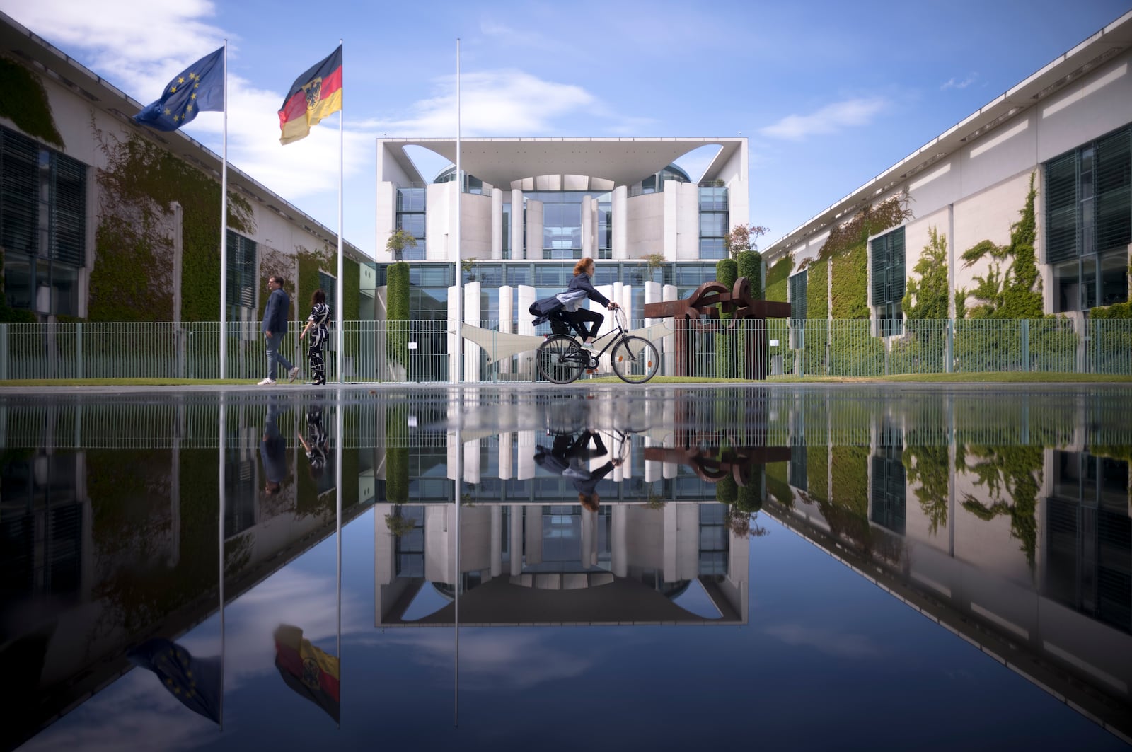 FILE - The Chancellery with the office of the German chancellors reflected in a puddle from a sprinkler on a sunny day in Berlin, Germany, June 13, 2023. (AP Photo/Markus Schreiber), File