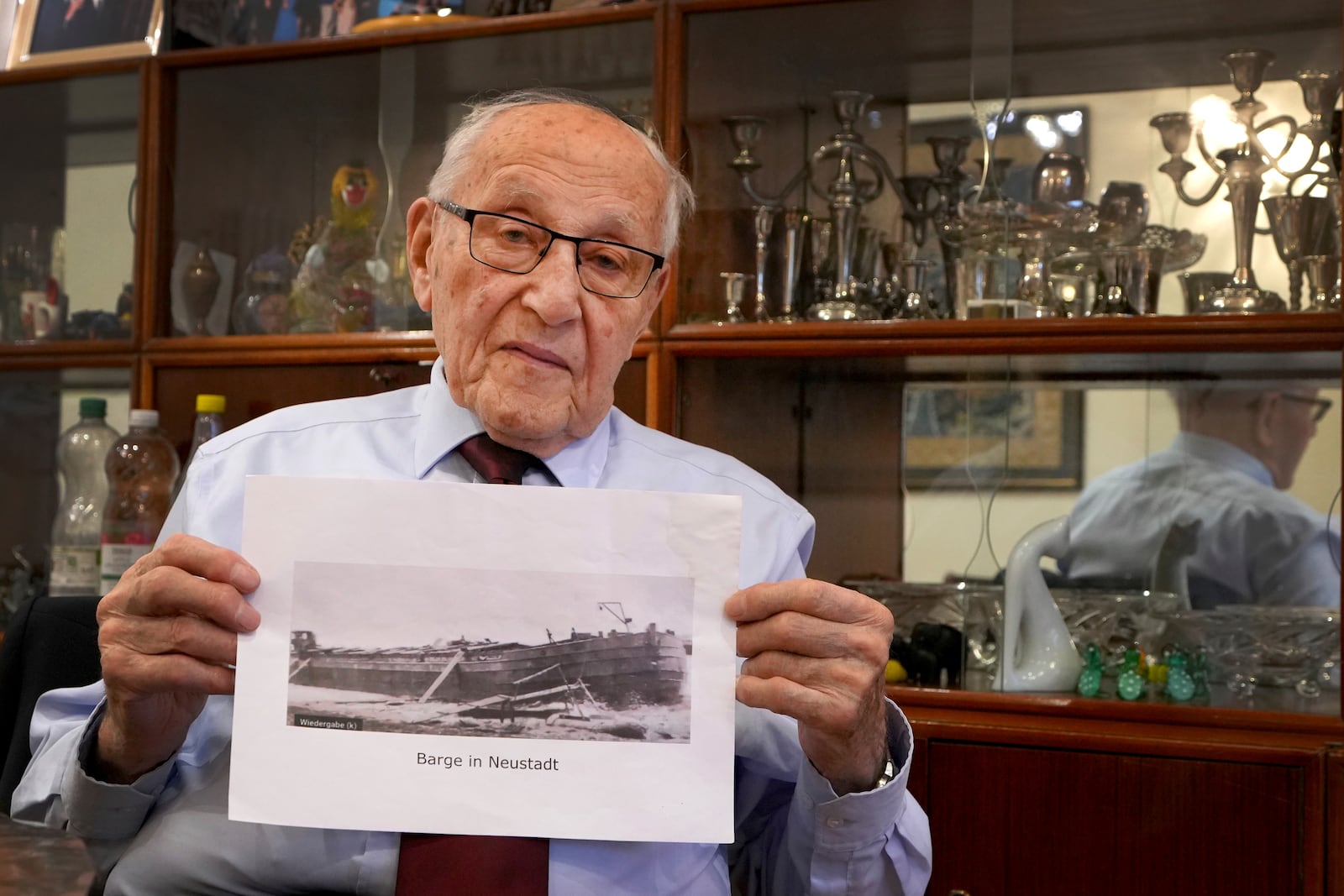 Manfred Goldberg, a Holocaust survivor displays a photograph of the barge in Neustadt, that he was transported on as he is interviewed in London, Wednesday, Jan. 22, 2025. (AP Photo/Kirsty Wigglesworth)